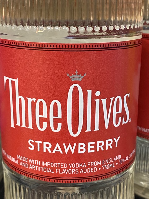 A close up of a bottle of three olives strawberry vodka