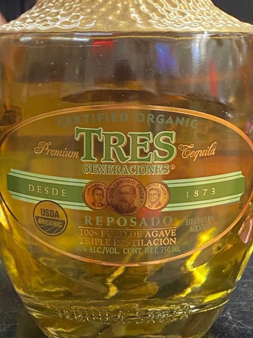 A bottle of tres tequila is sitting on a table.