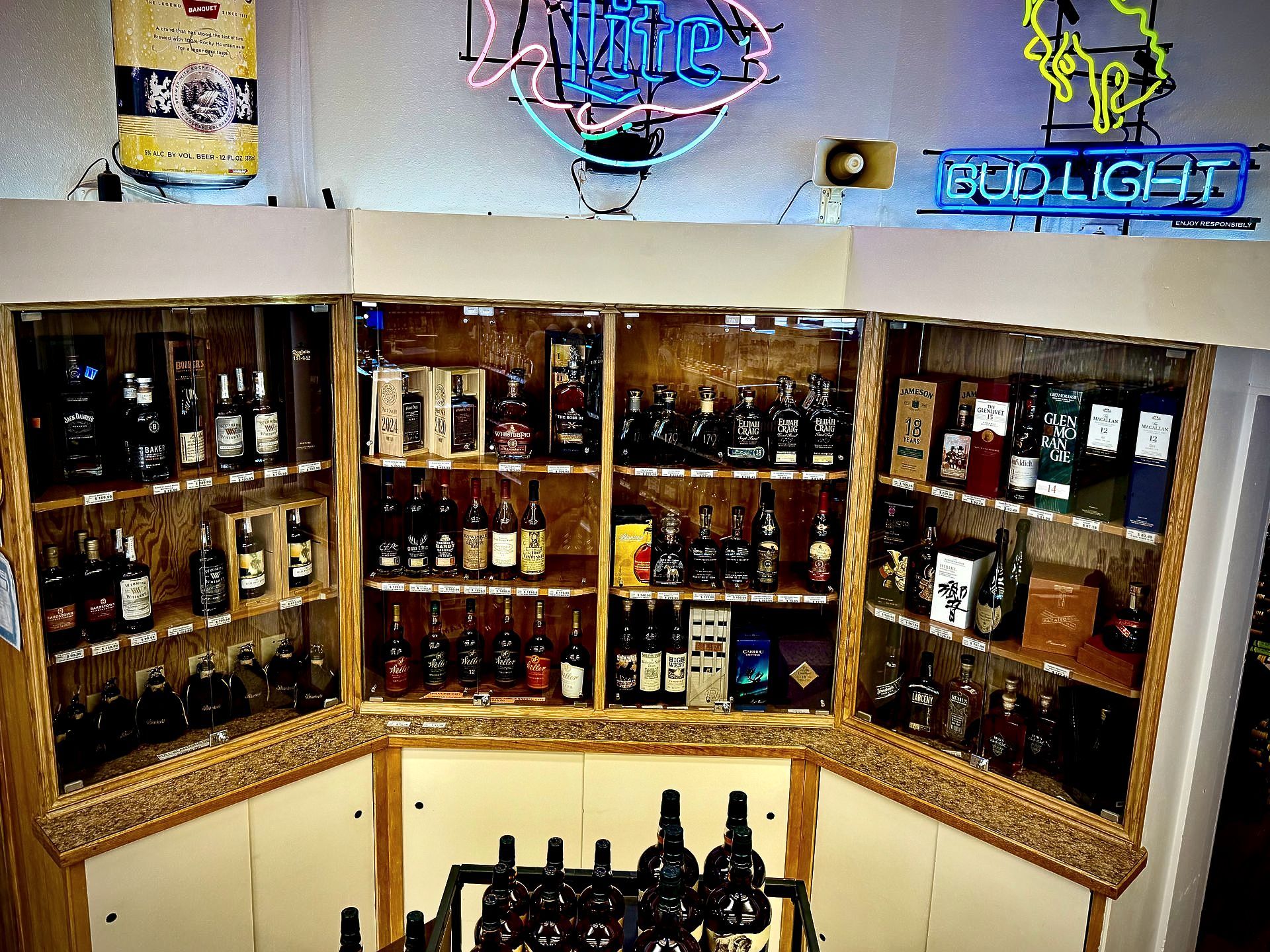 A bud light sign hangs above a display of liquor bottles