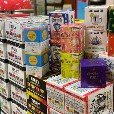 A variety of alcoholic beverages are stacked on top of each other in a store.