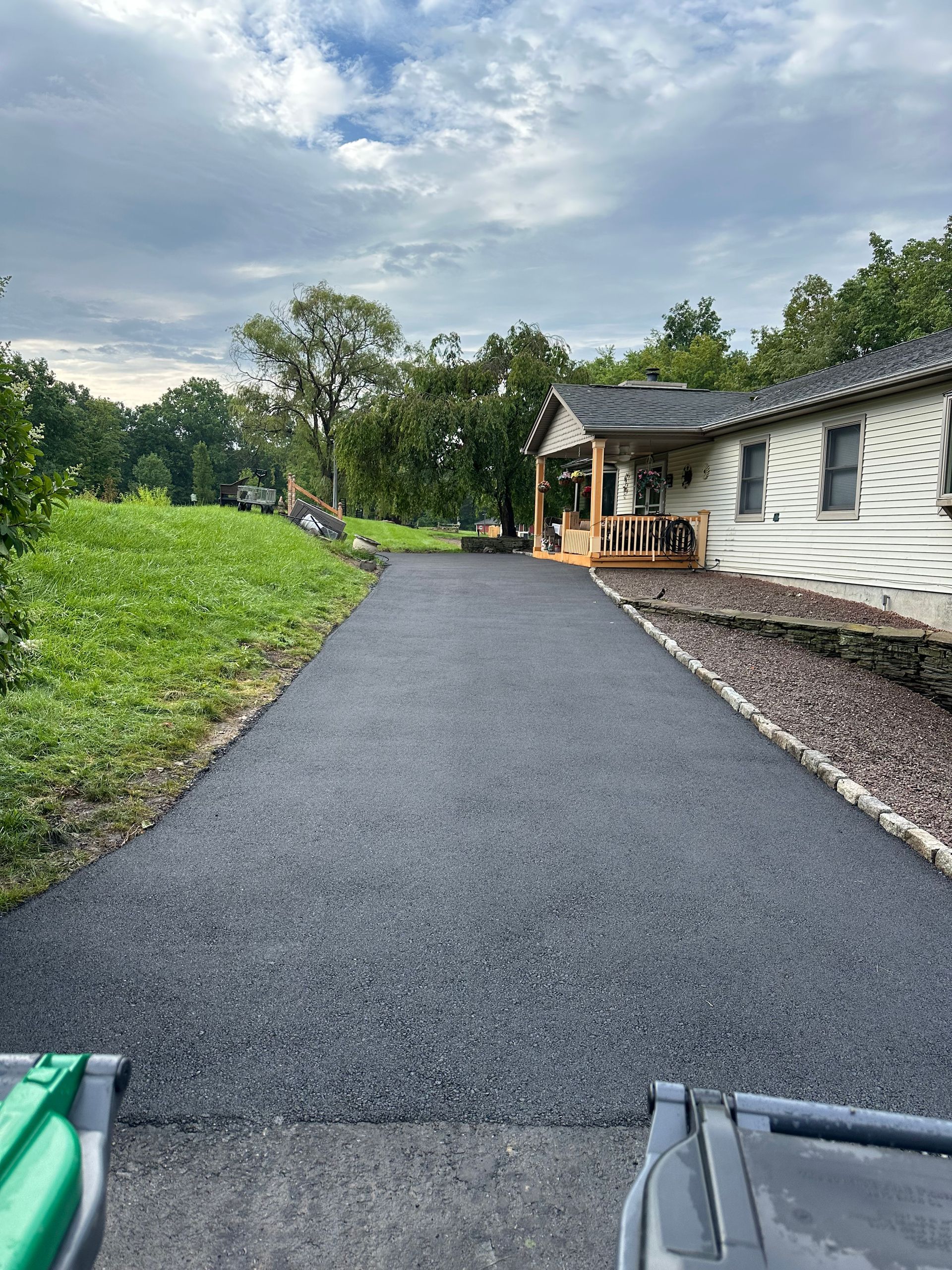 A driveway leading to a house with a porch.