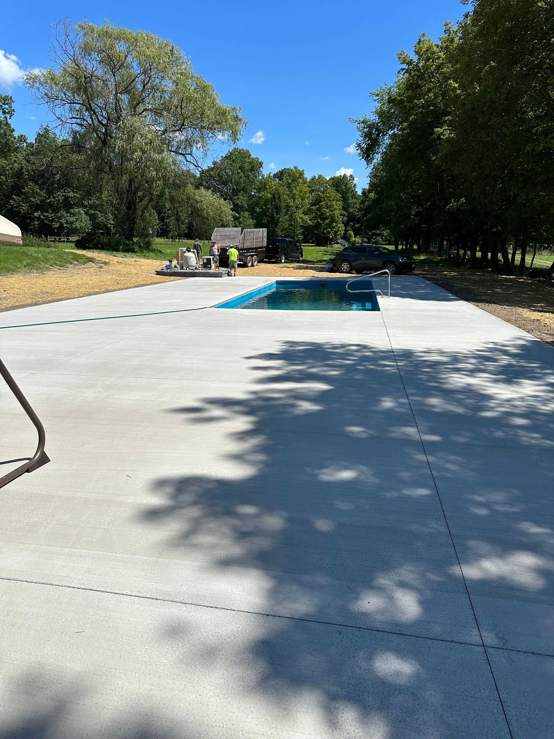 A concrete driveway with a swimming pool in the background