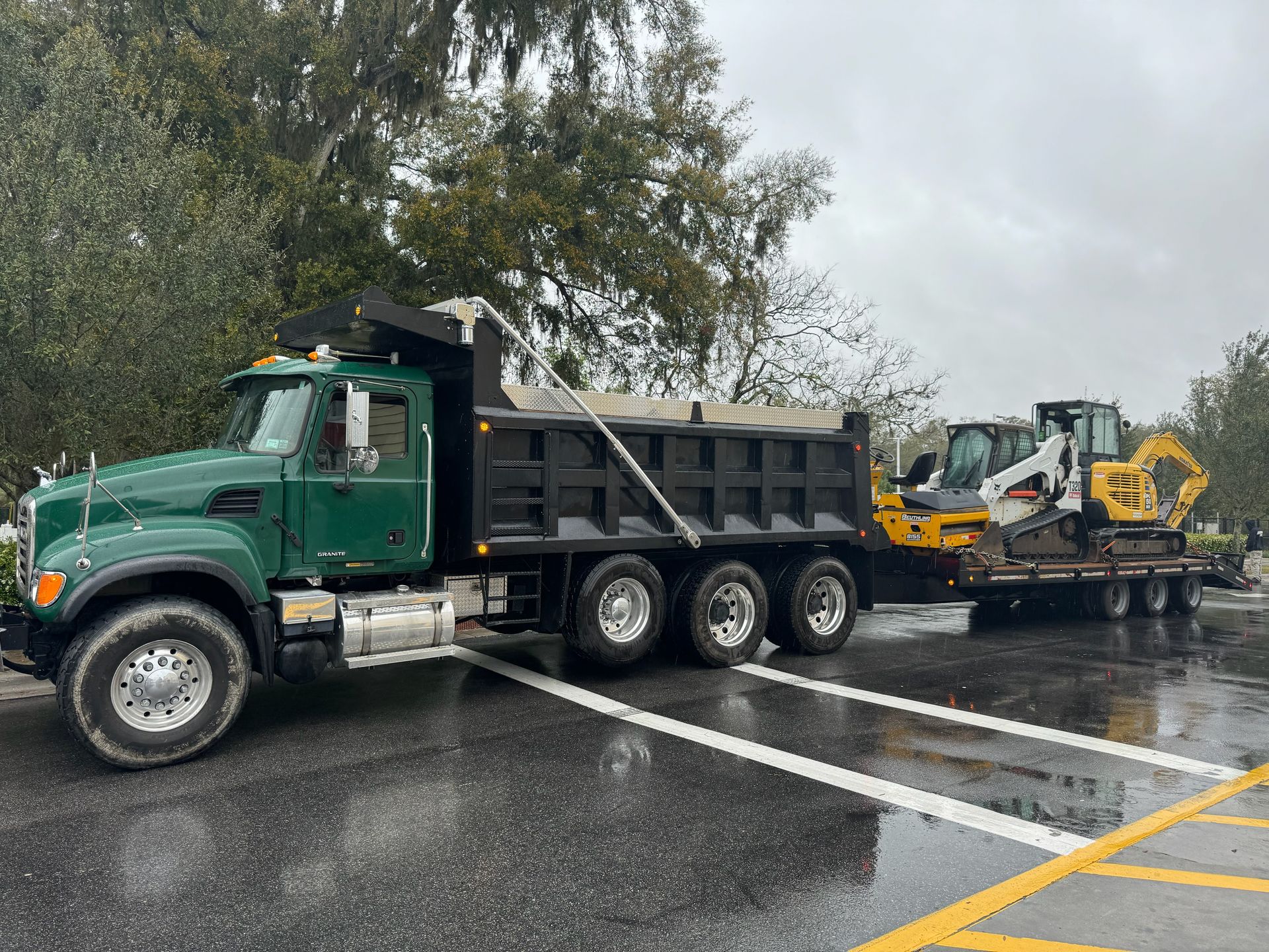 A dump truck is parked in a parking lot next to a bulldozer.