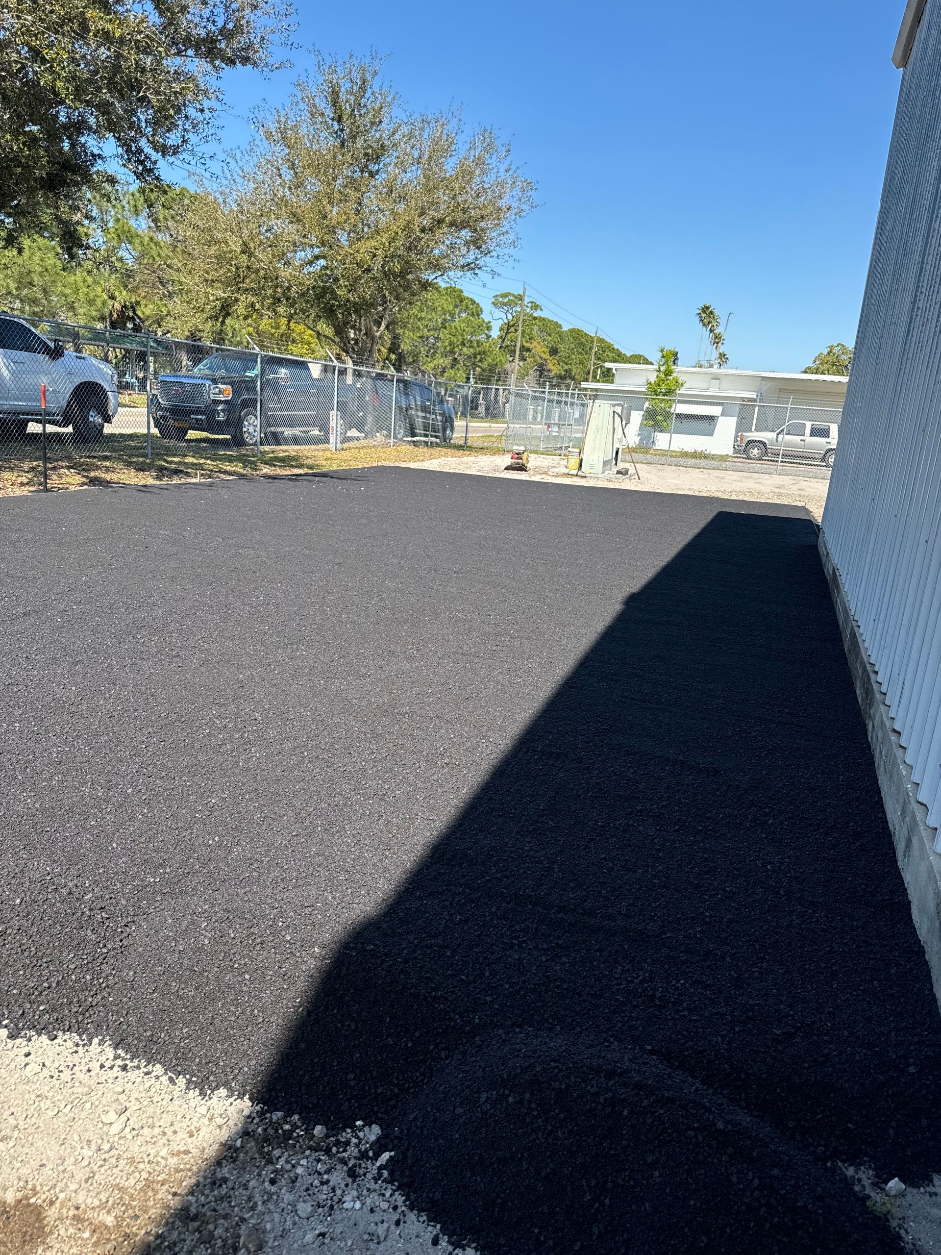 A large pile of black gravel is sitting in front of a white building.