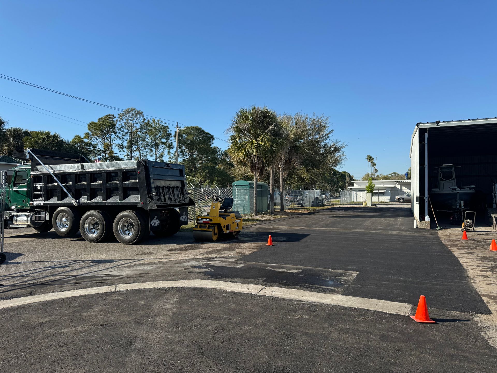 A dump truck is parked in a parking lot next to a trailer.
