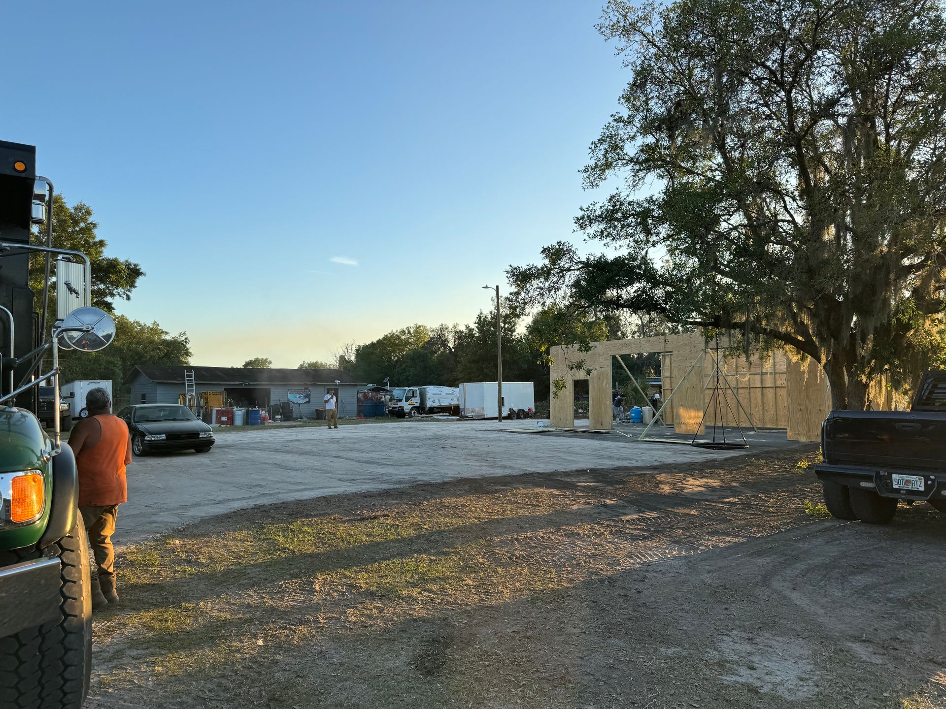 A truck is parked in a gravel lot in front of a building under construction.