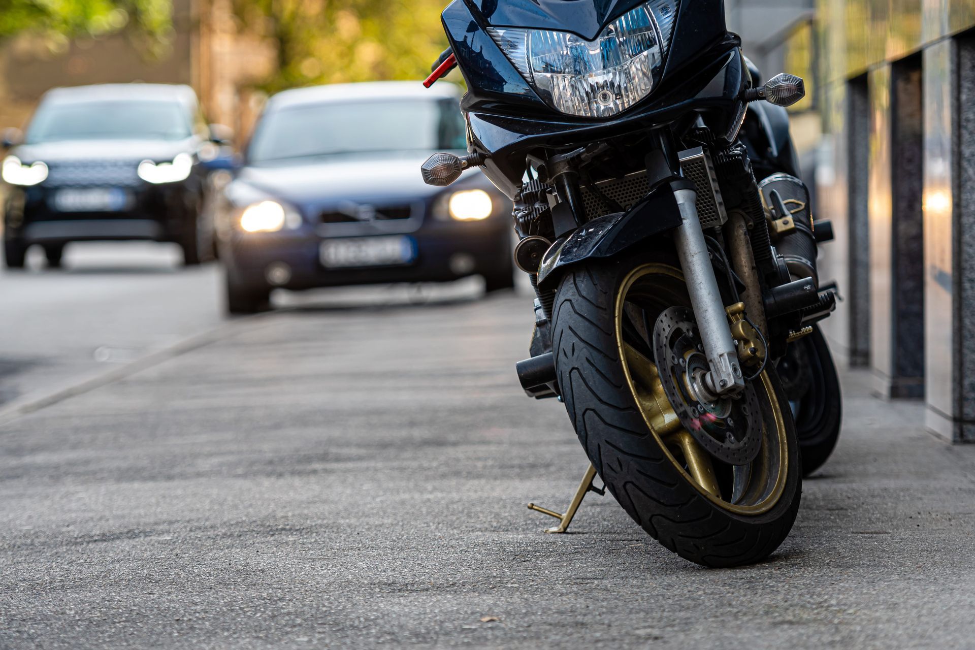 Black motorcycle parked on a city street with cars blurred in the background