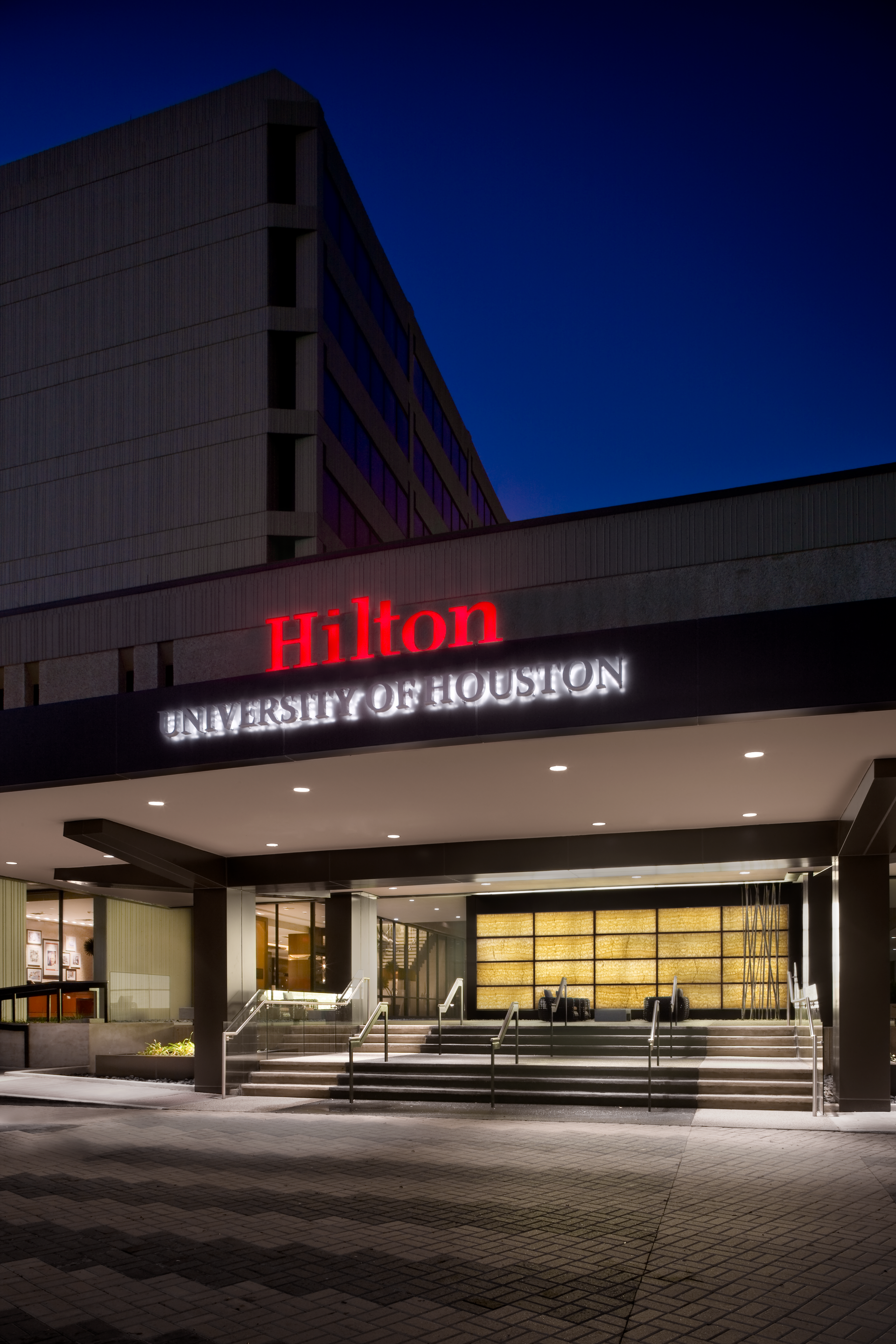 A courtyard with chairs and tables in front of a building at night