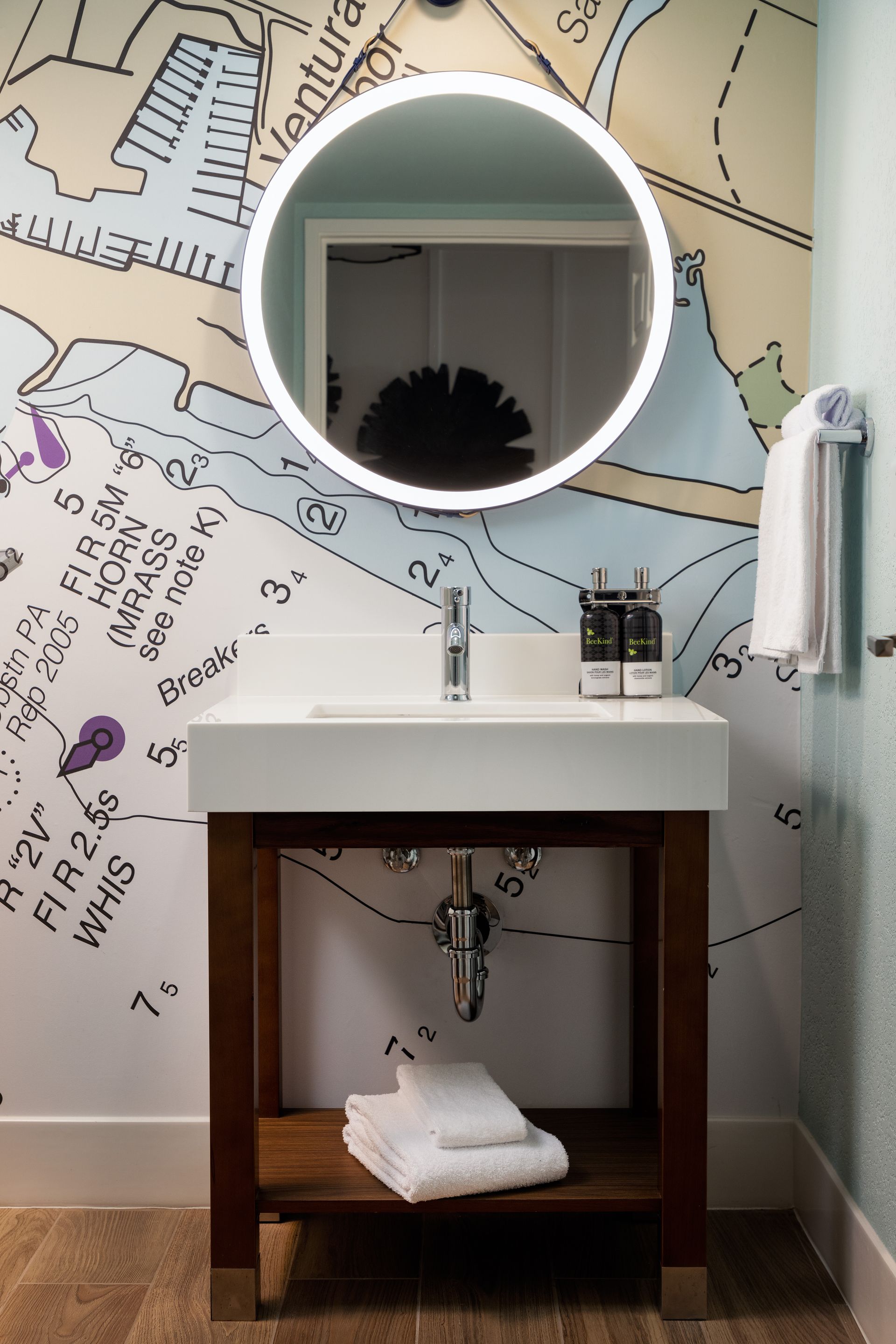 A bathroom with a sink , mirror and a map on the wall.