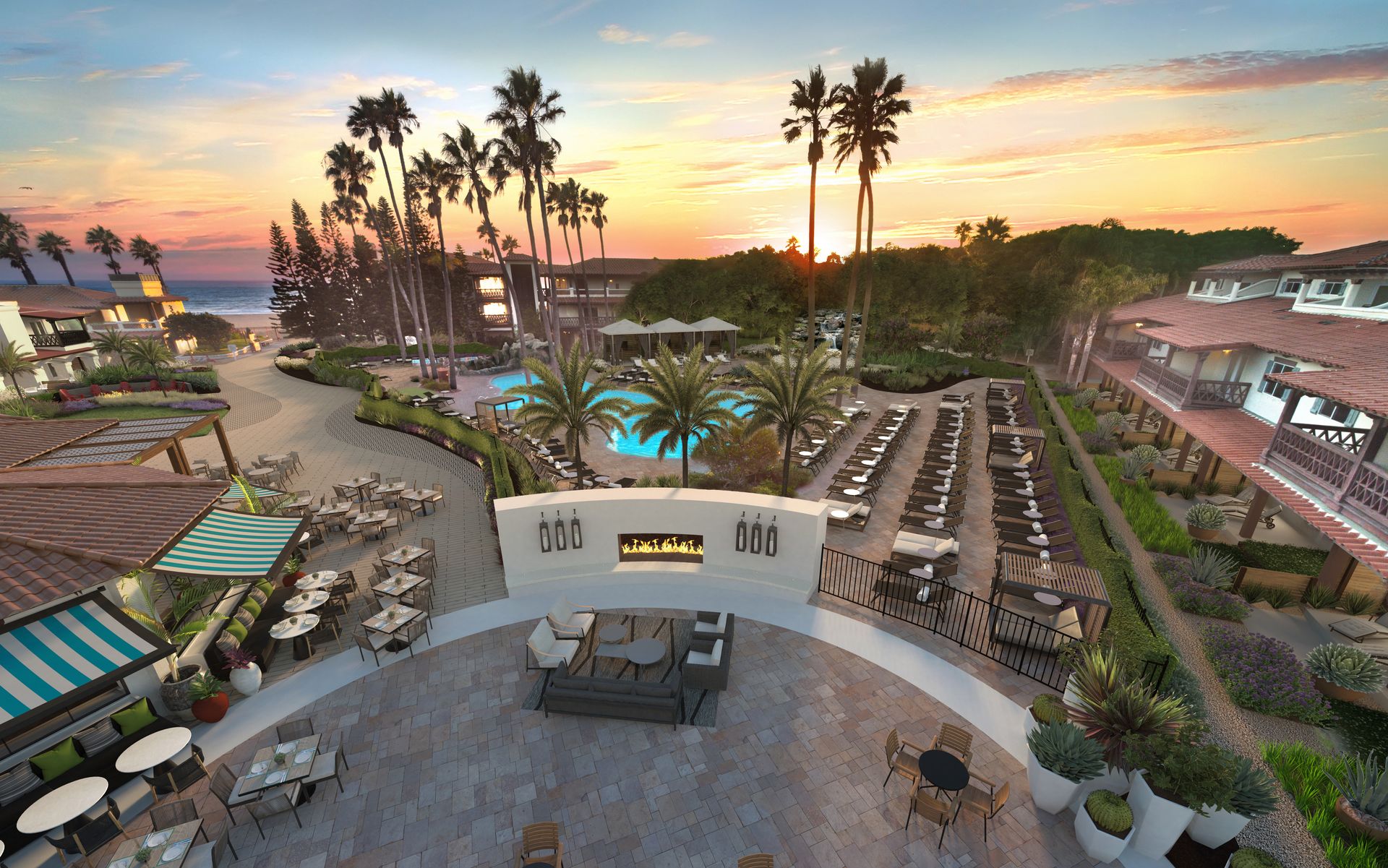 An aerial view of a resort with palm trees and a fireplace at sunset.