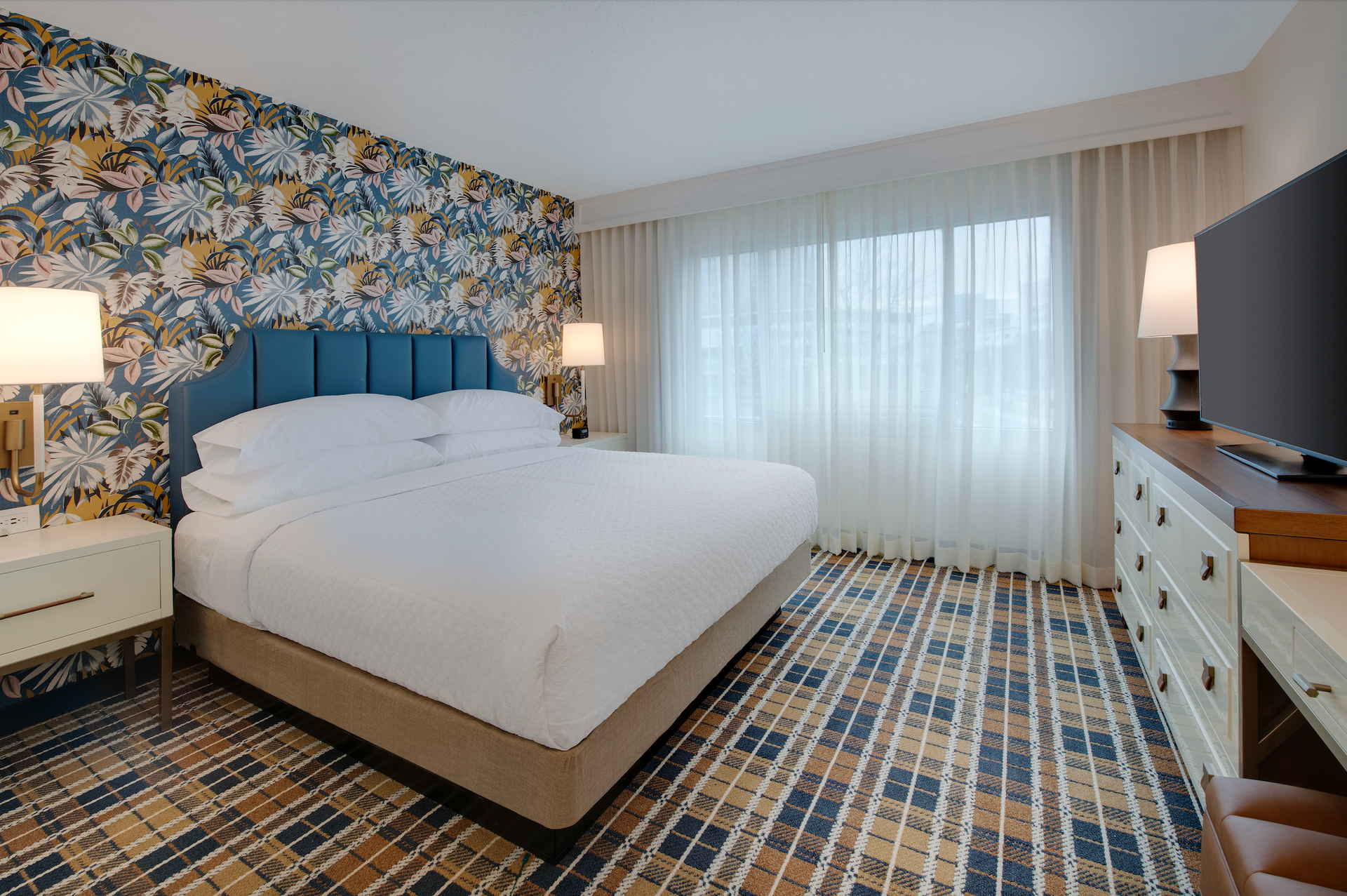 A hotel room with a king size bed and a flat screen tv.