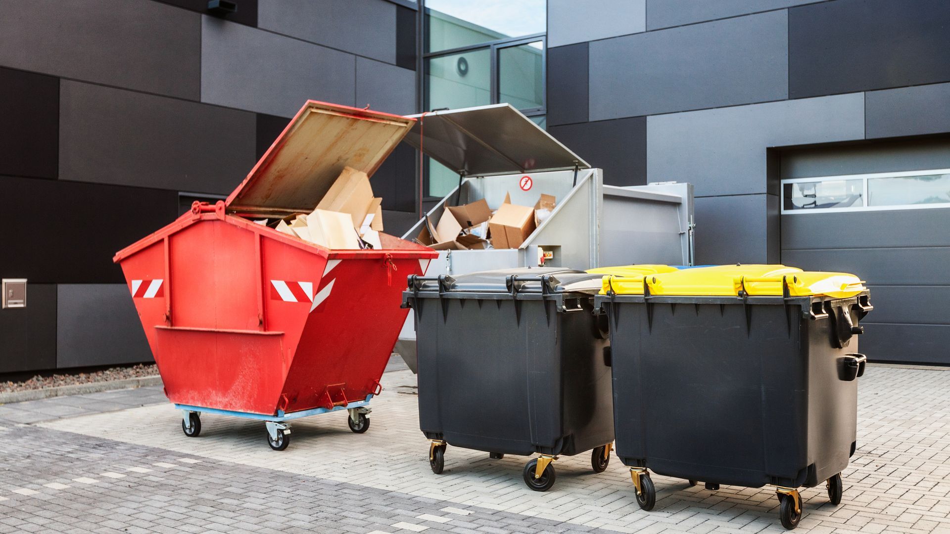 A group of dumpsters are parked in front of a building.
