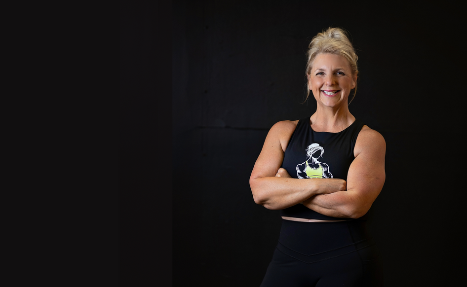 Tracy T is standing with her arms crossed in front of a black wall.