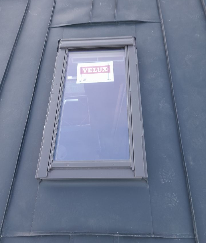 Primo piano di un lucernario VELUX grigio incastonato in un tetto scuro.
