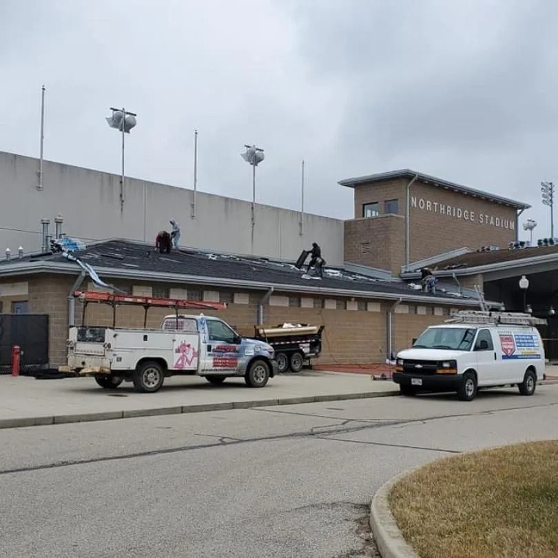 Workers repair the roof of a stadium building marked 