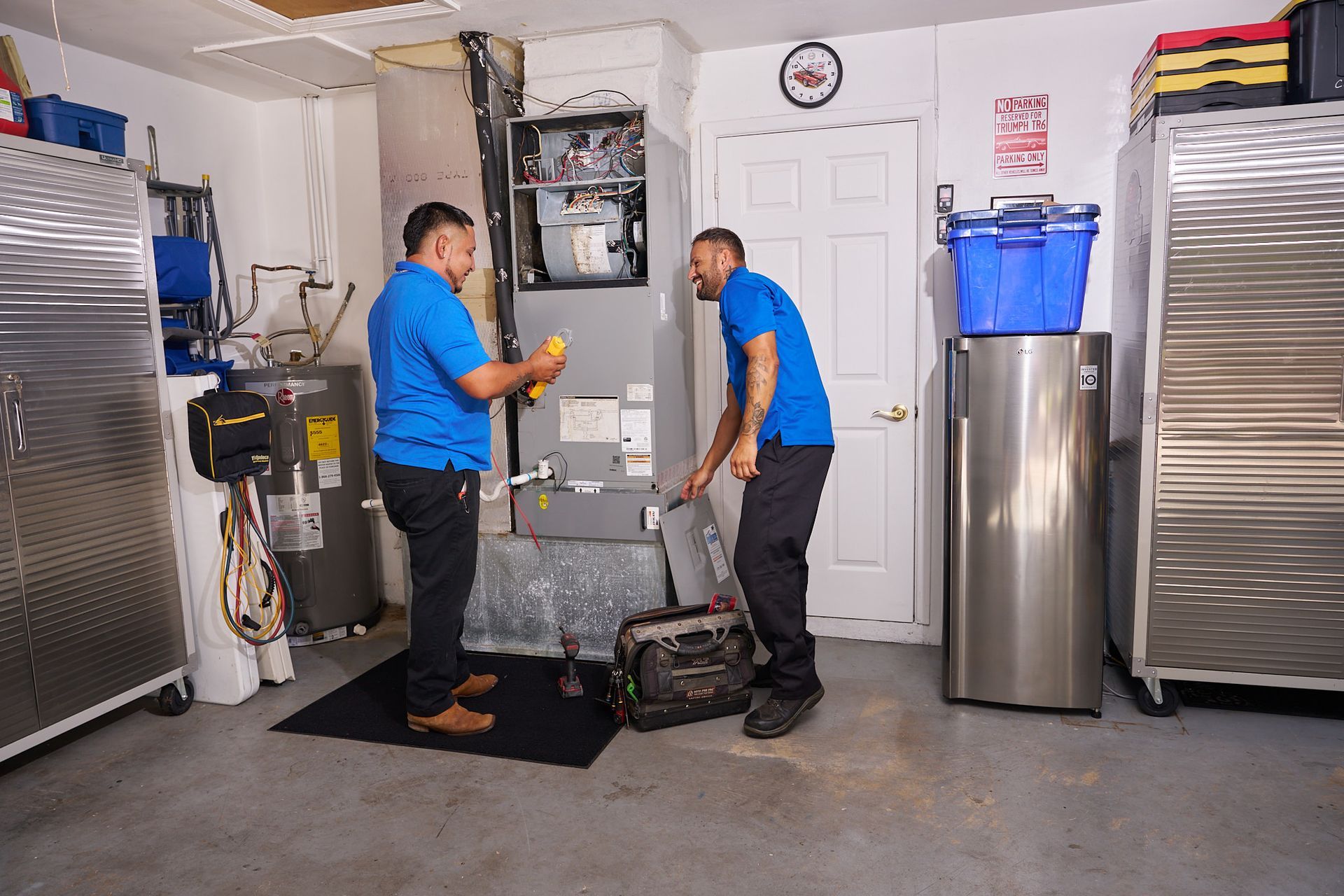 Technician inspecting an HVAC furnace with tools in a basement utility area