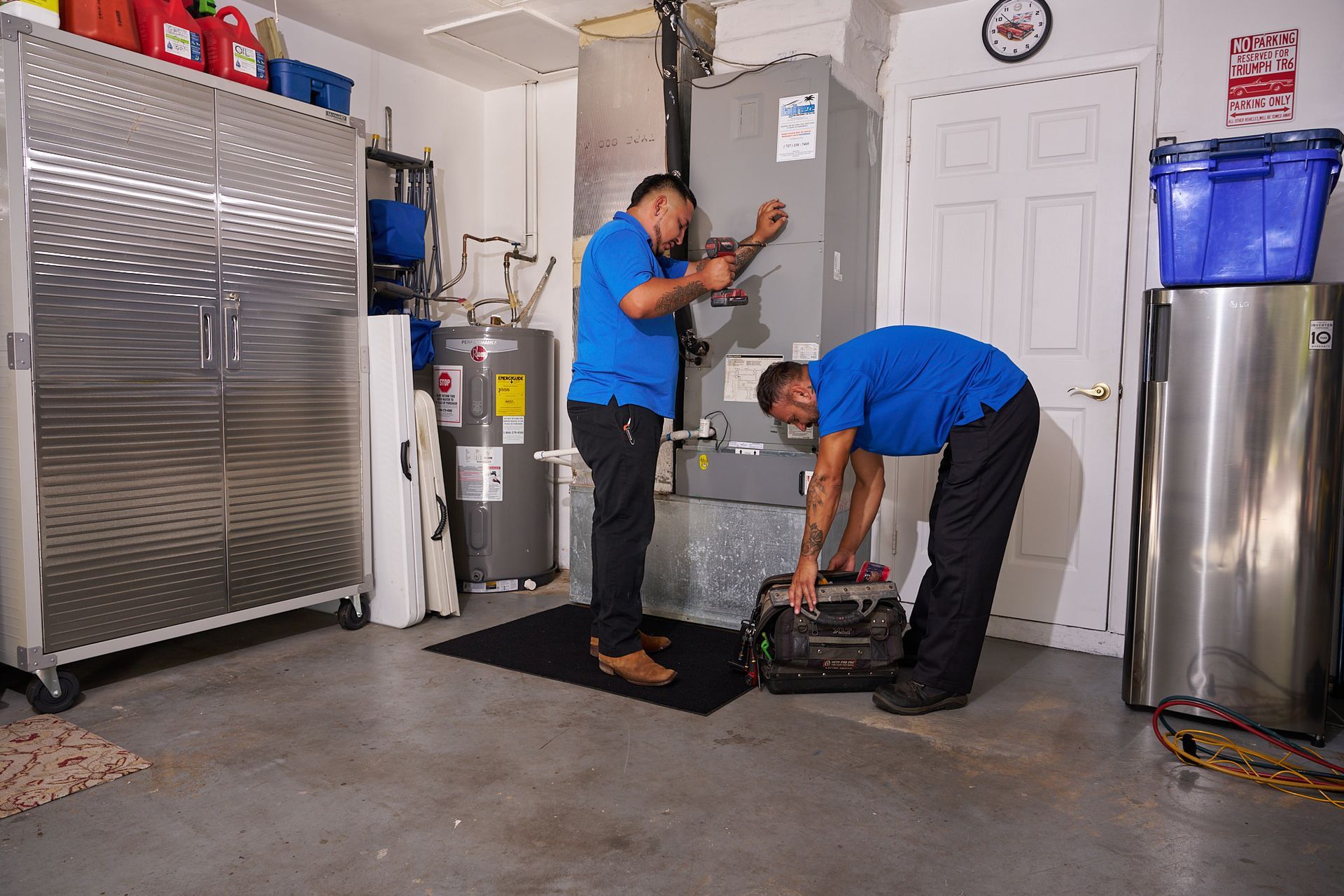 Technician inspecting a furnace in a utility room with tools in hand