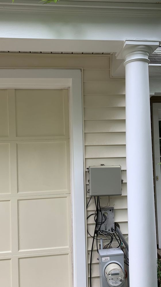 Front porch of a house with white siding, a column, and electrical meters mounted on the wall.