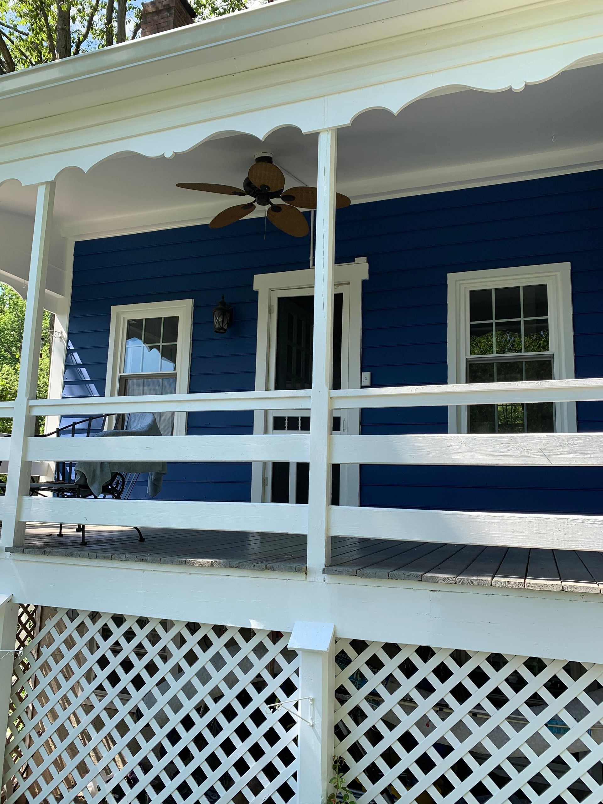 Blue house porch with white railings and lattice, and a bird perched under the roof eave.