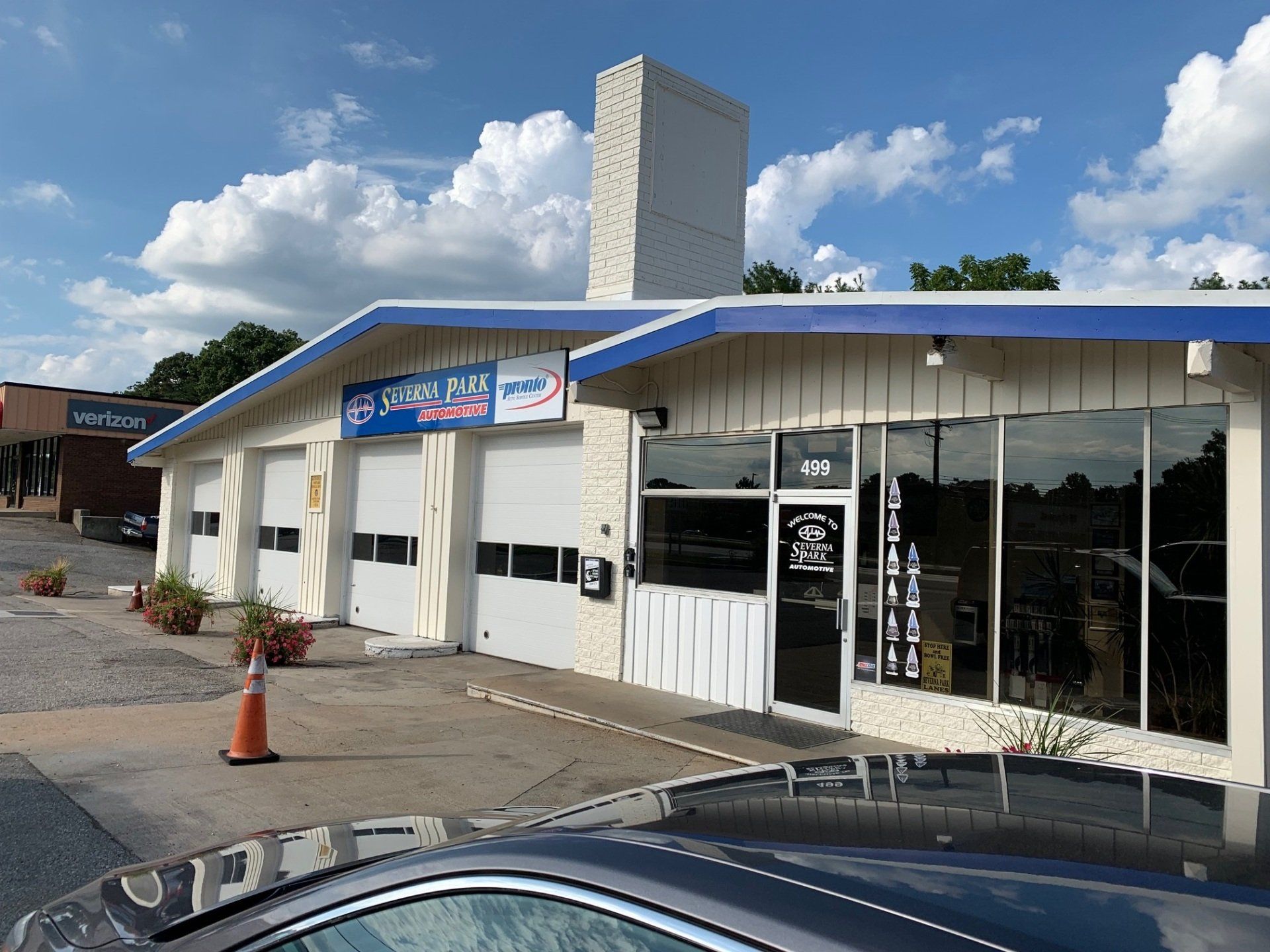 Small storefront with a white facade, blue awning, and glass entrance under a partly cloudy sky.