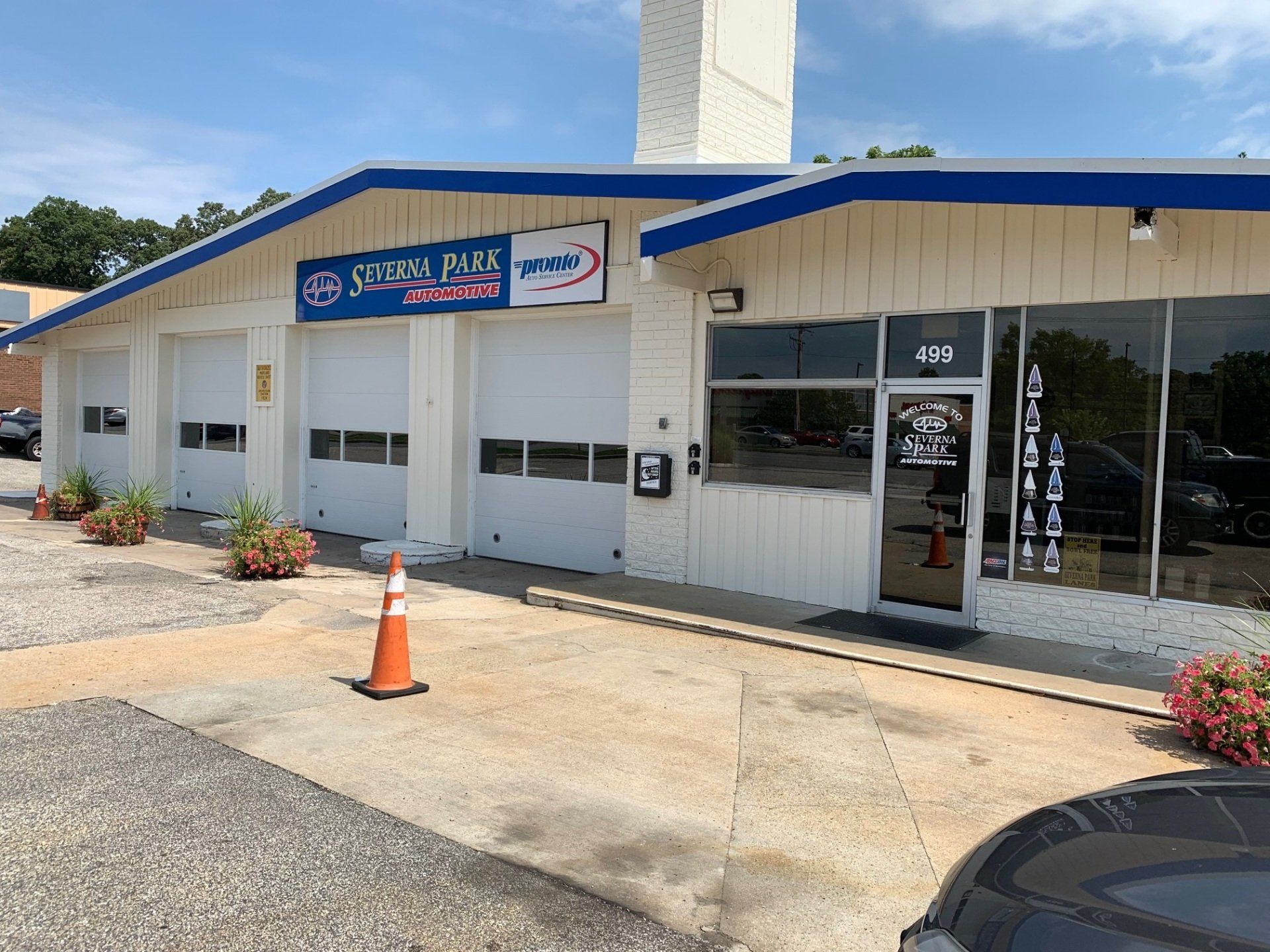Small strip mall storefront with blue roof, glass doors, and an orange traffic cone outside
