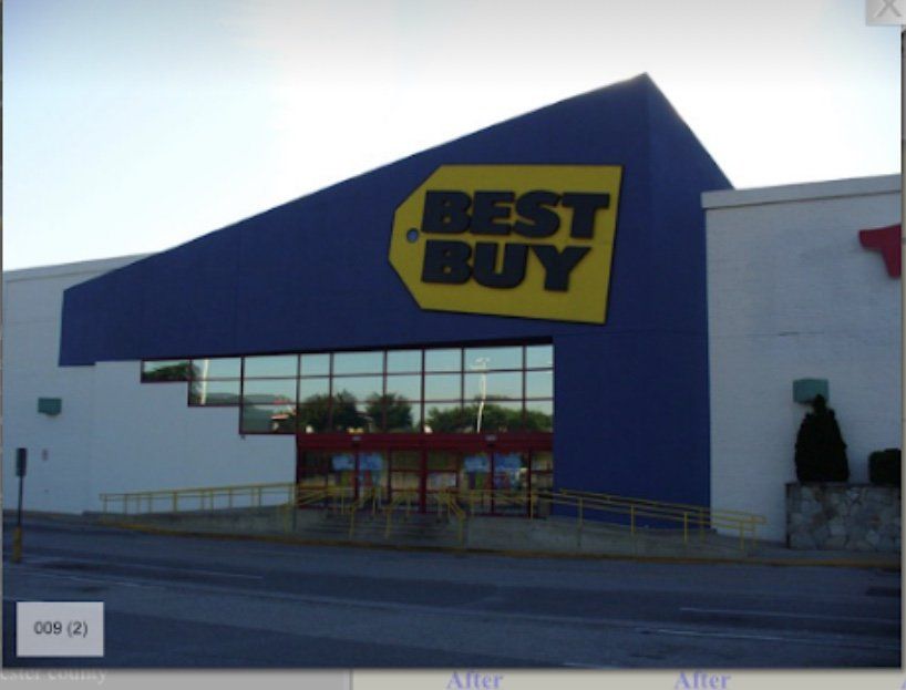 Best Buy storefront with blue facade and yellow logo, seen from the parking lot