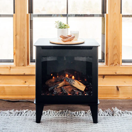 An electric fireplace is sitting in front of a window in a living room.