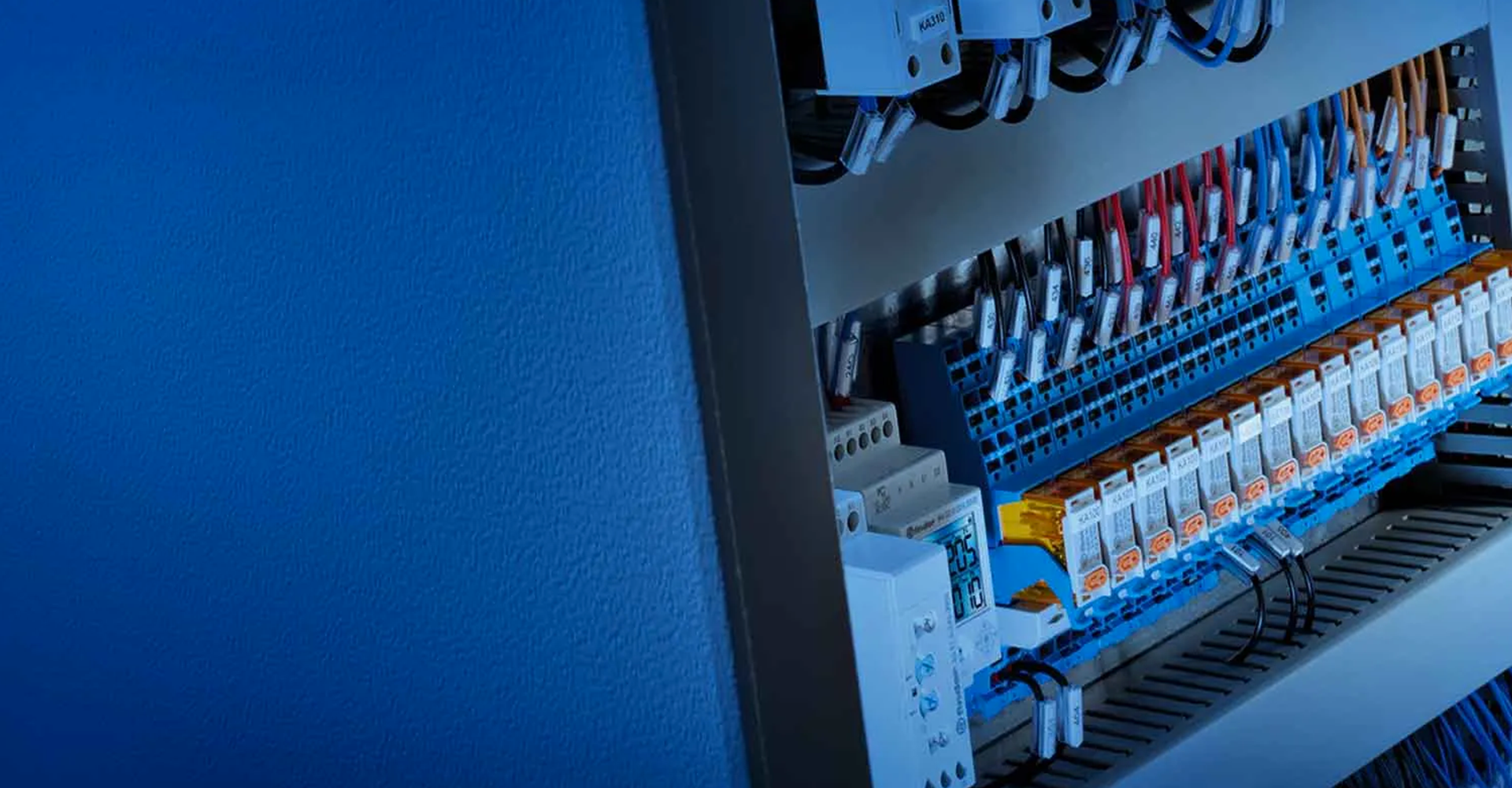 Primer plano de un panel de control eléctrico con cableado ordenado, con bloques de terminales azules y cables multicolores.