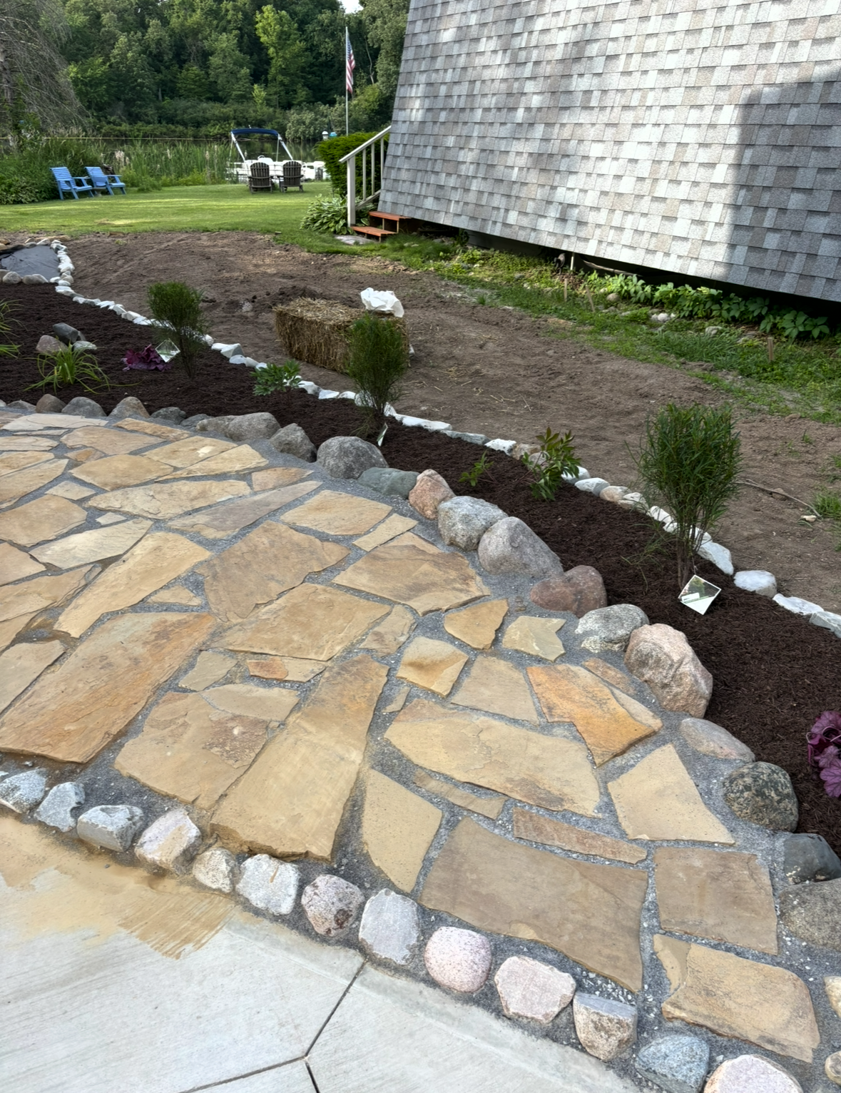 Stone garden path beside landscaped flower bed and gray-shingled building.