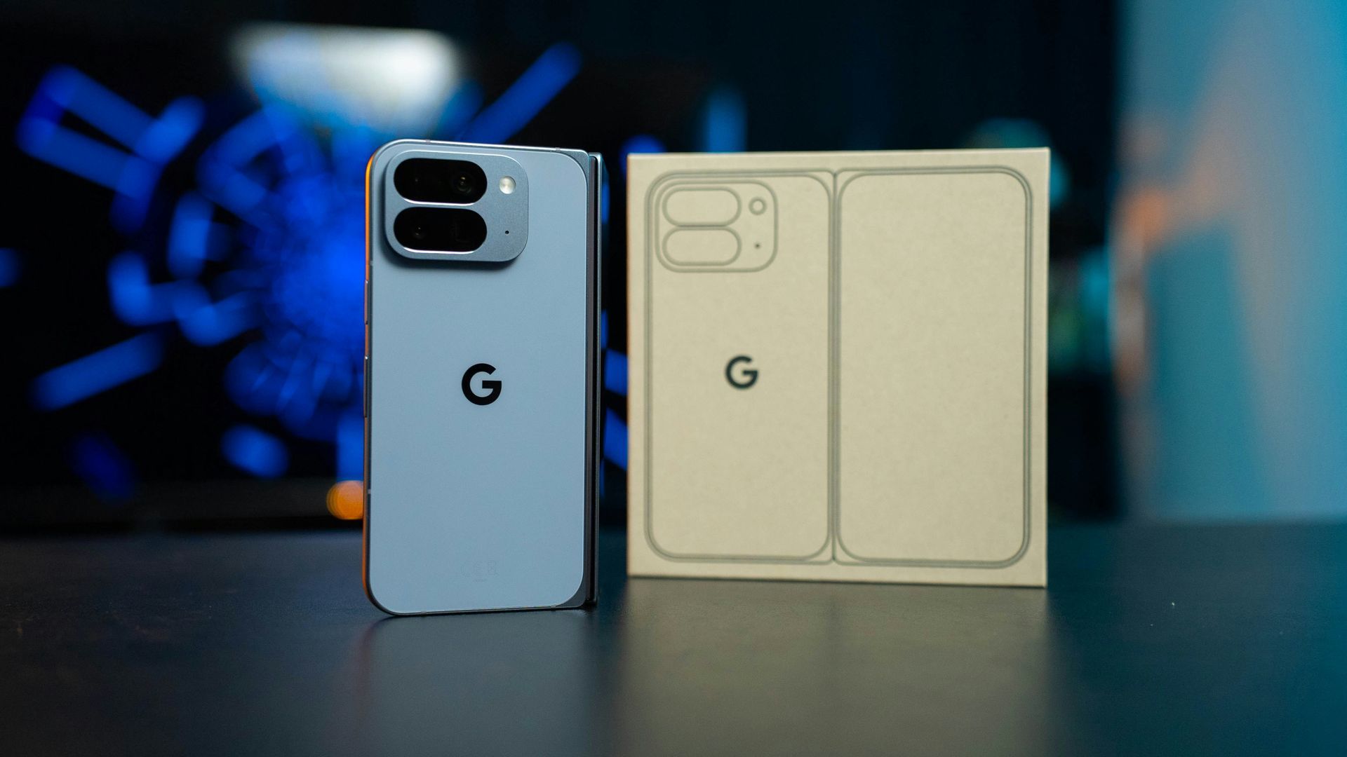 Two smartphones on a table, one light blue and one beige, against a blurred blue background.