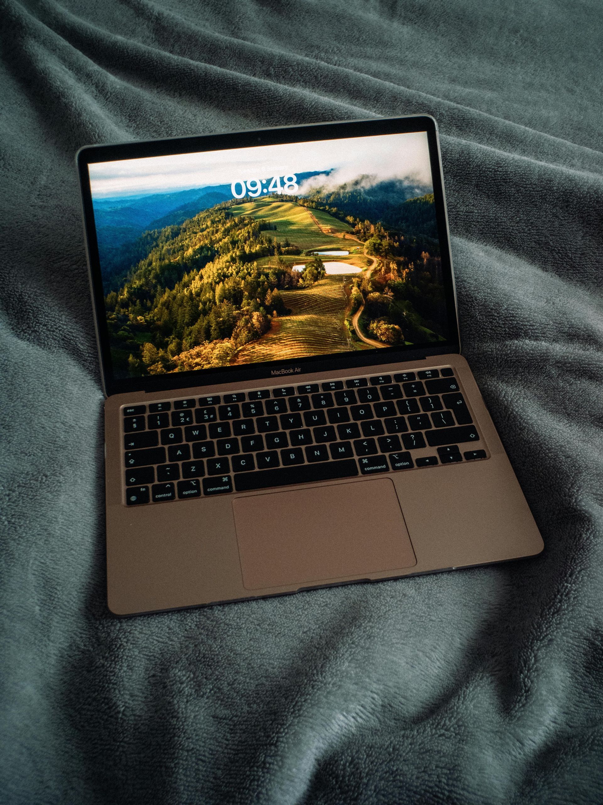 Open laptop on dark fabric with a scenic landscape on the screen