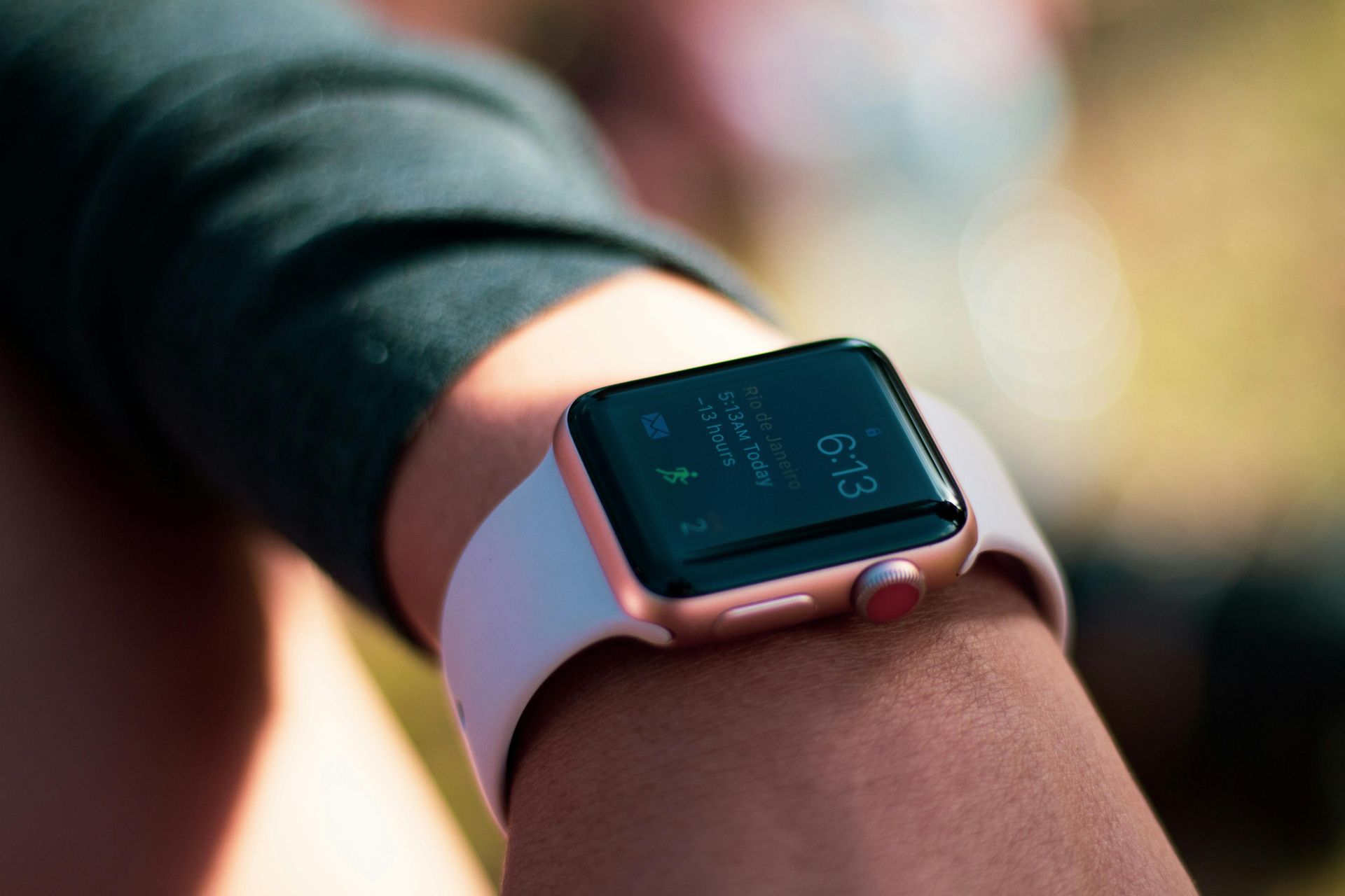 Close-up of a wrist wearing a rose gold smartwatch with a light pink band