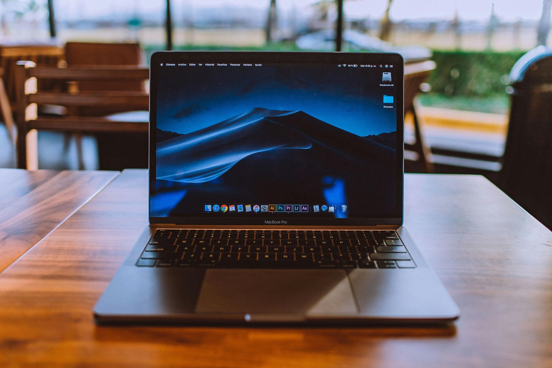 Laptop on a wooden table in a café, showing a blue desktop screen.