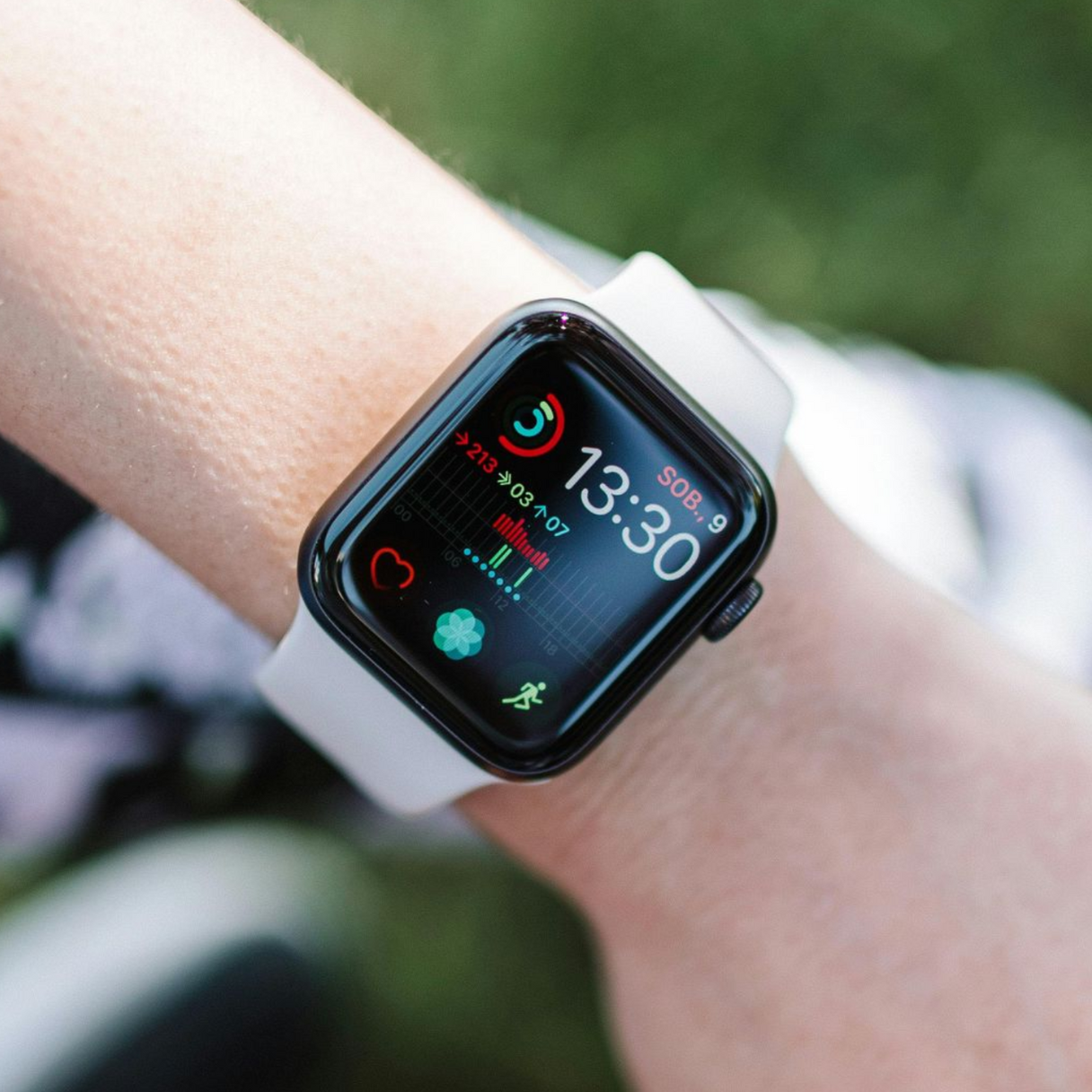 Close-up of a smartwatch on a wrist, showing a colorful fitness watch face outdoors.