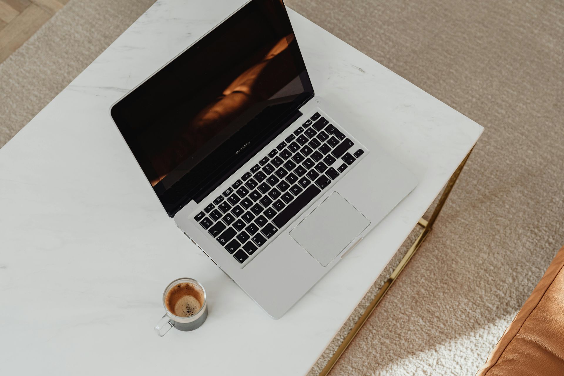 Laptop on a white table beside a cup of coffee, viewed from above.