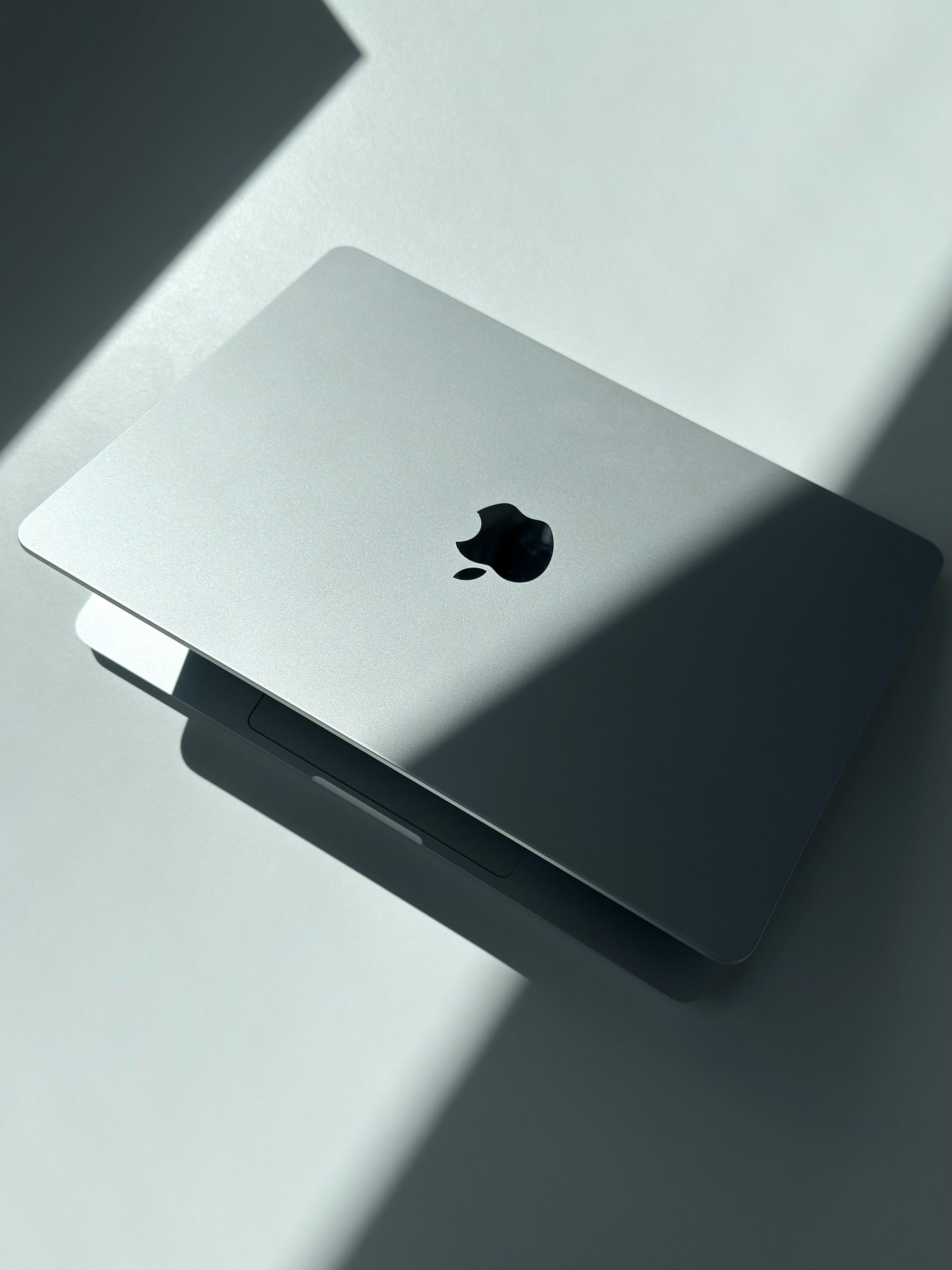 Silver MacBook on a sunlit surface with the Apple logo visible
