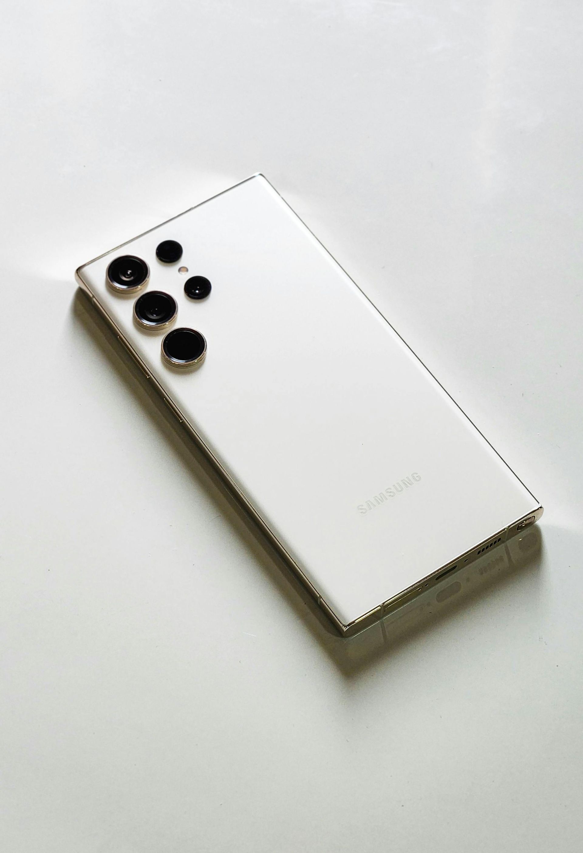 White smartphone with multiple rear cameras on a light background