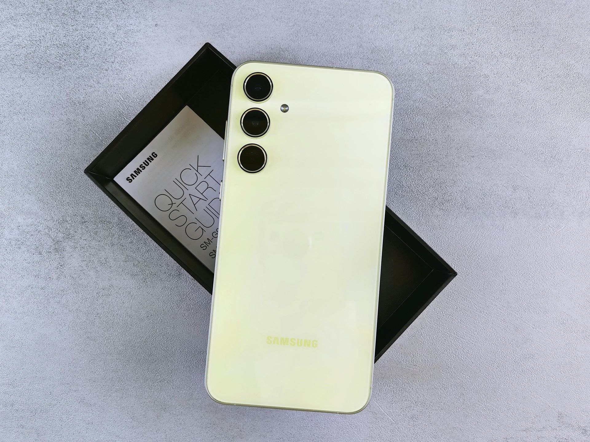 Light yellow smartphone with triple cameras on a black phone box