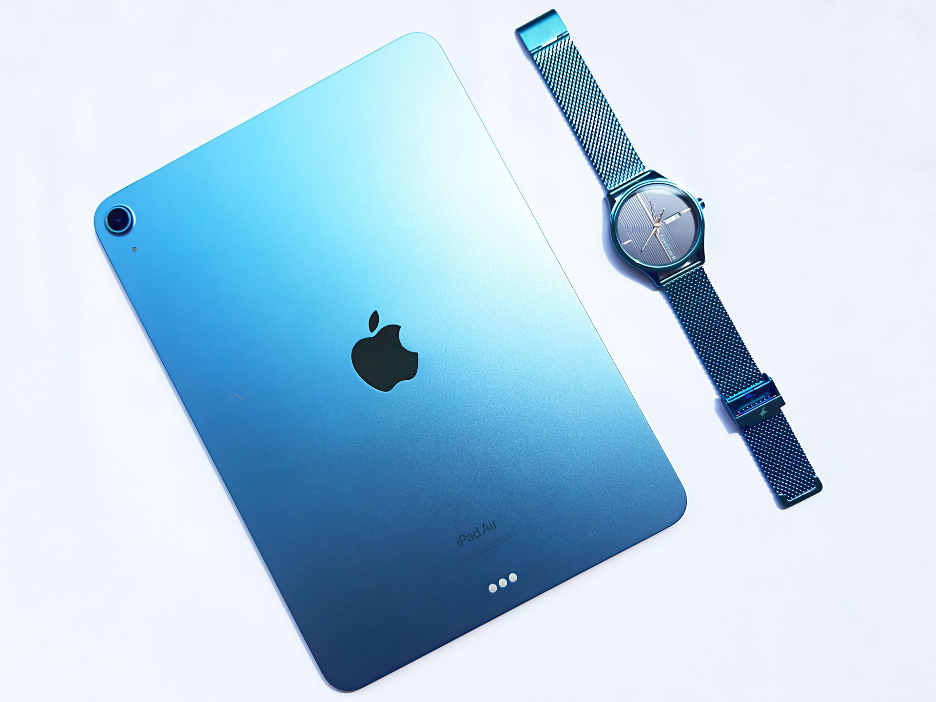 Blue iPad and matching blue Apple Watch on a white background