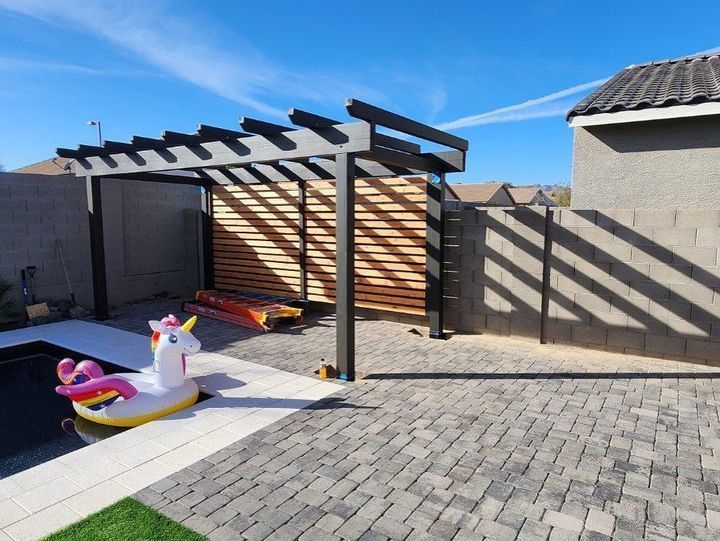 A unicorn float is sitting under a pergola next to a pool.