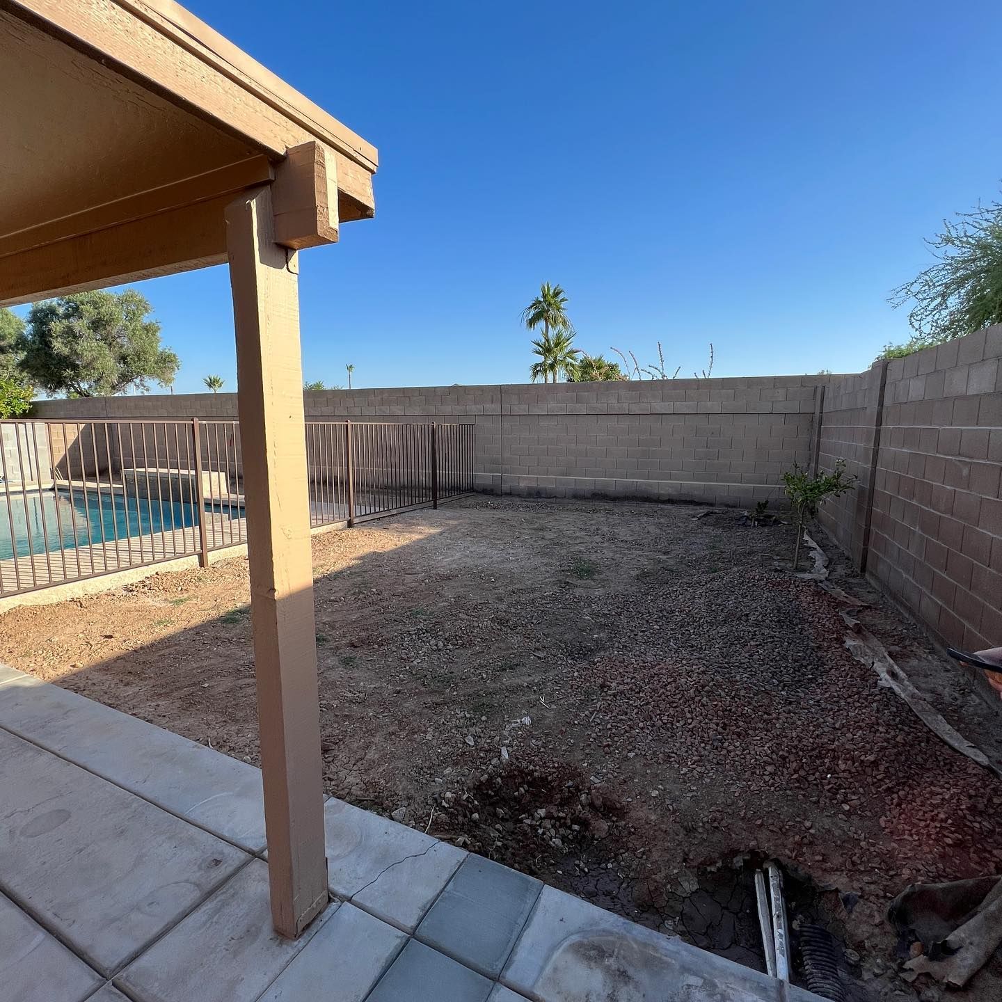 A backyard with a fence and a pool in the background