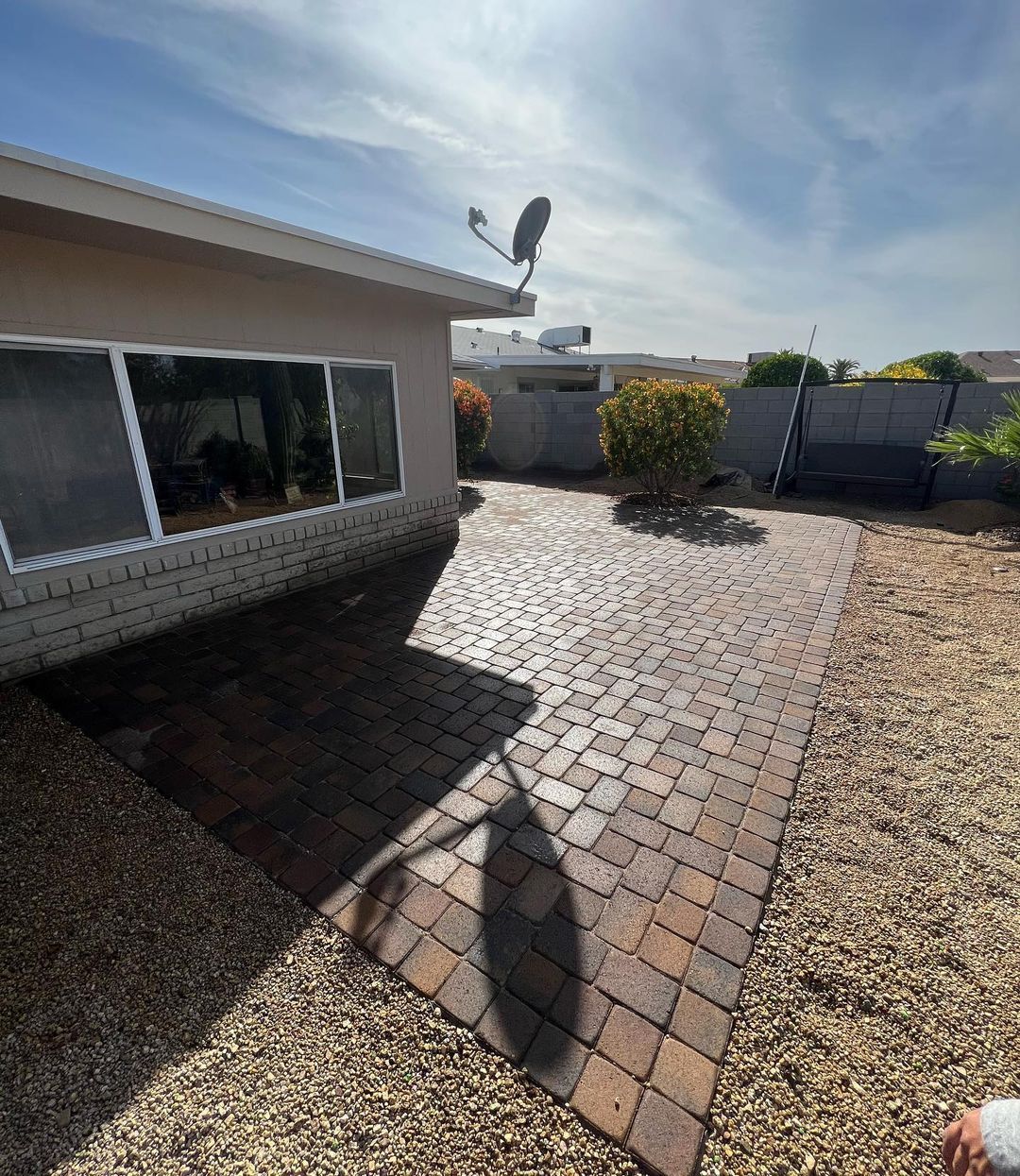 A person is standing in front of a house with a satellite dish on top of it.