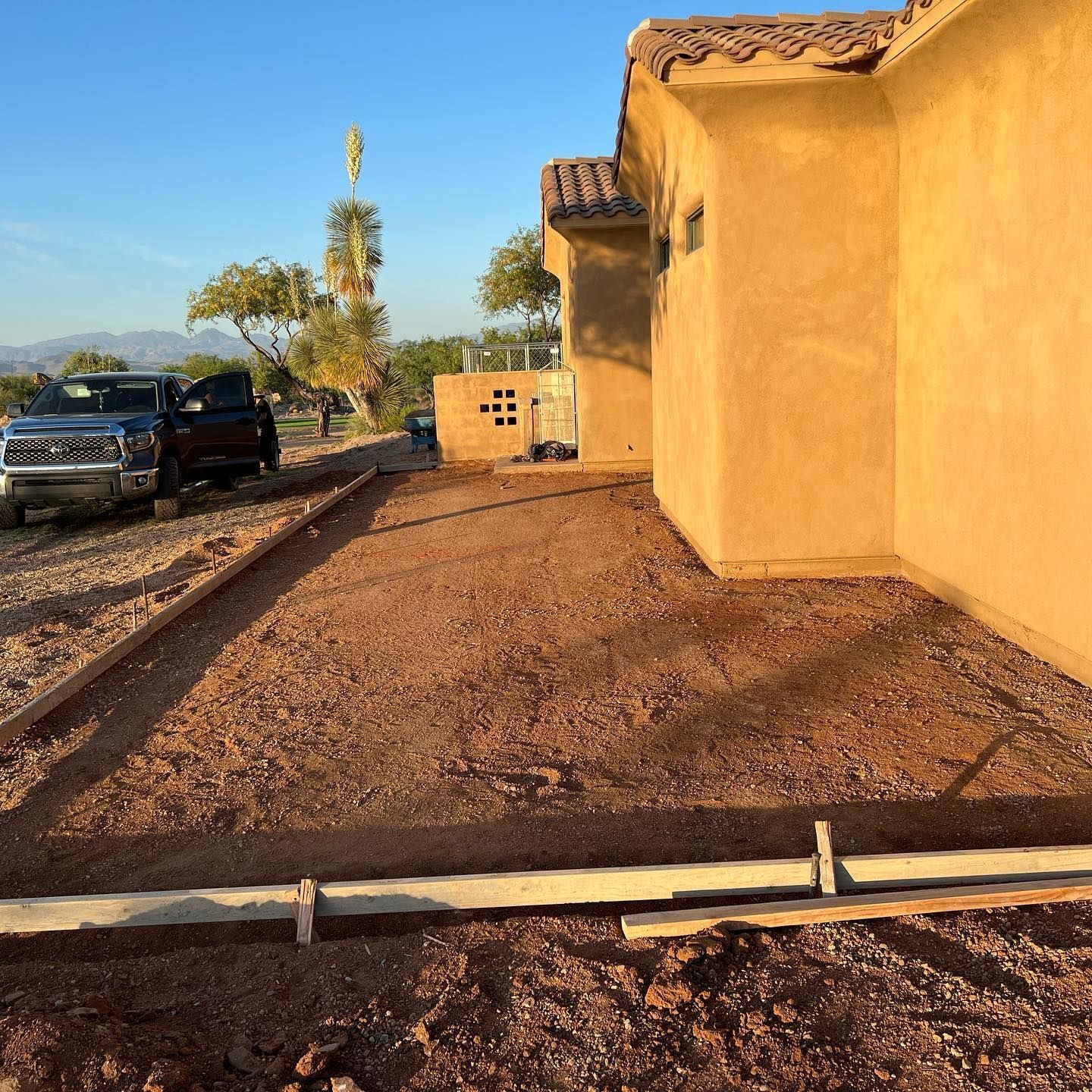 Two trucks are parked in front of a house that is being built