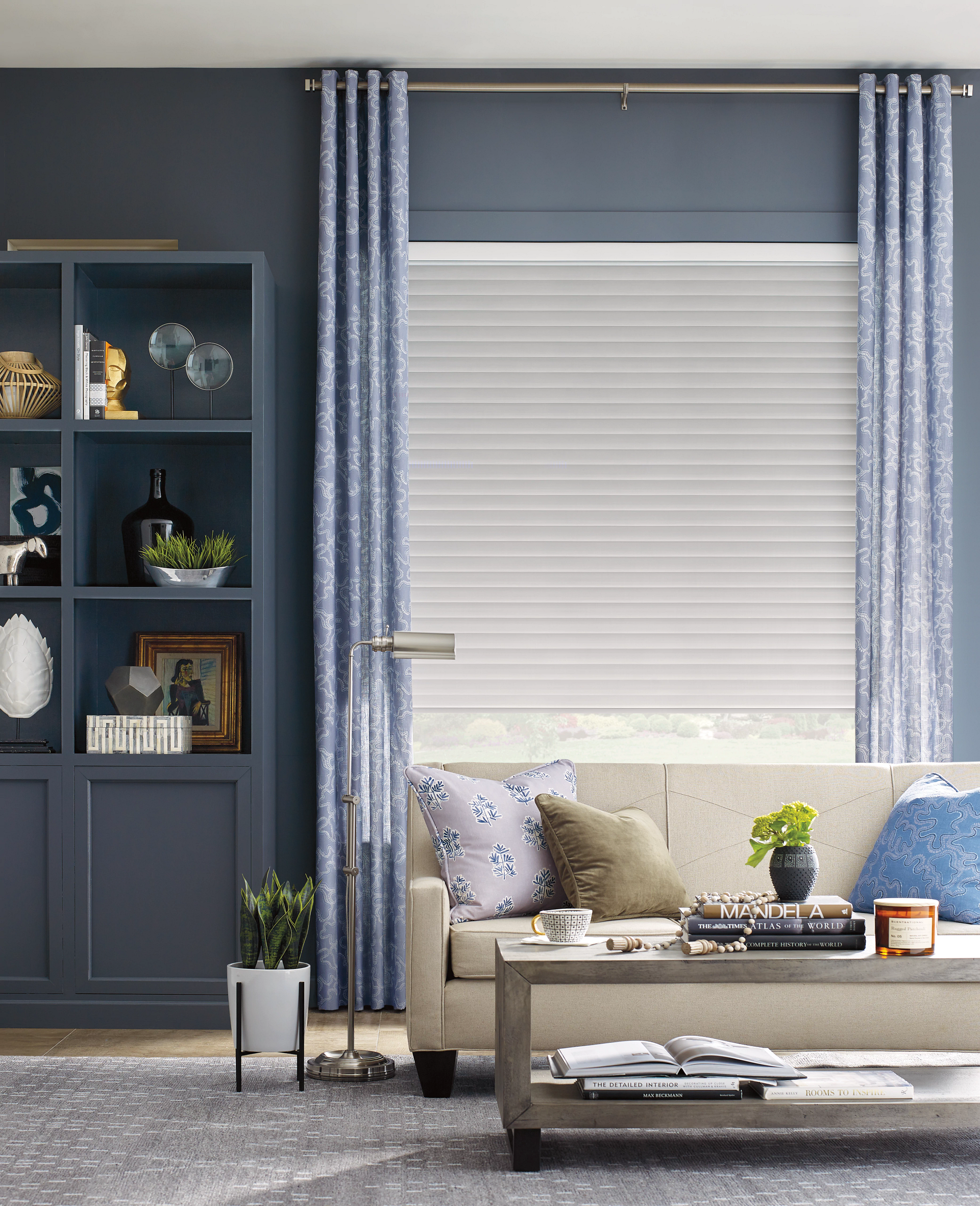 Living room with blue walls, patterned curtains, neutral couch, and modern furniture.