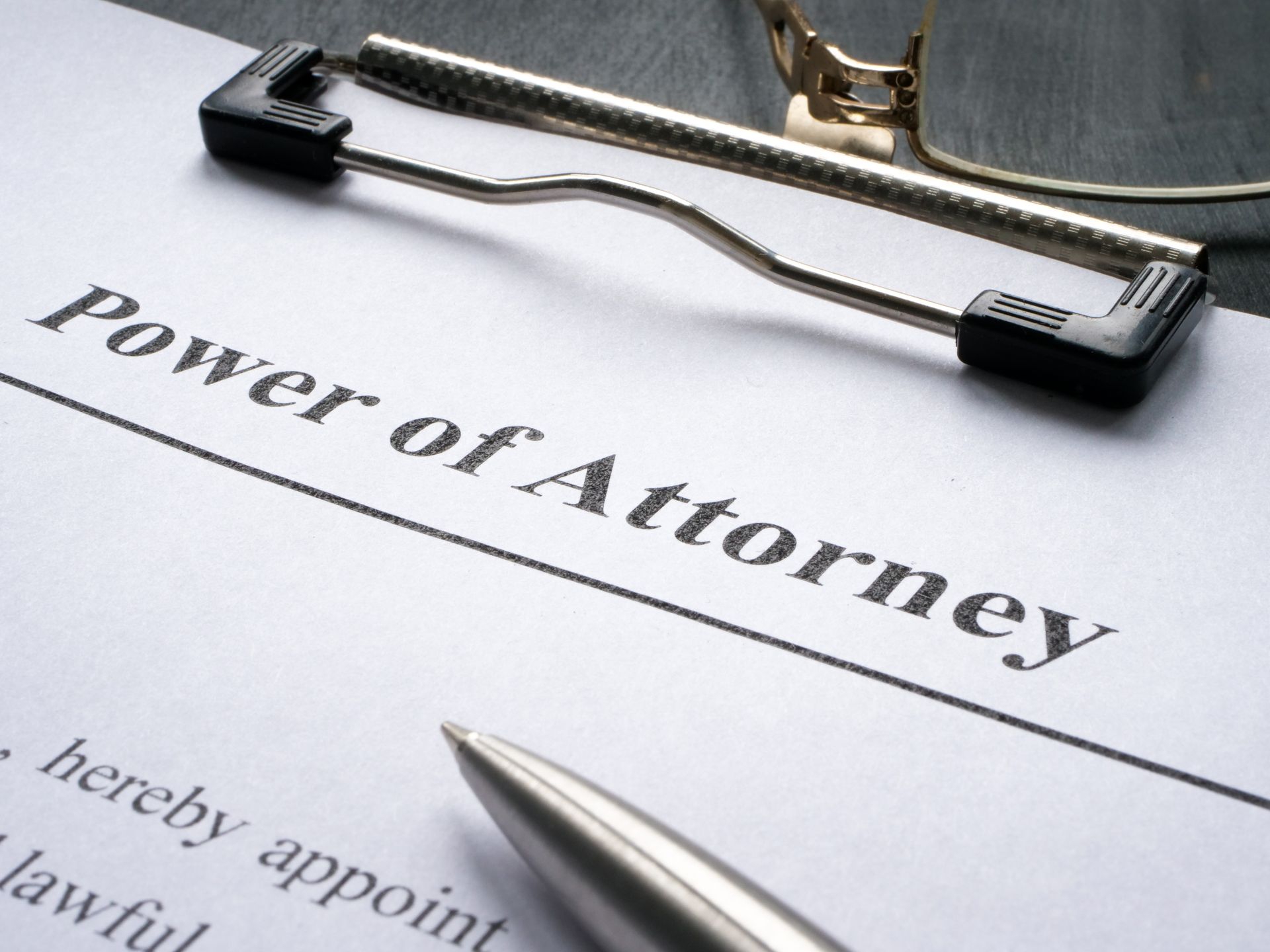 Power of Attorney document on a clipboard with a pen and glasses, preparing for signing.