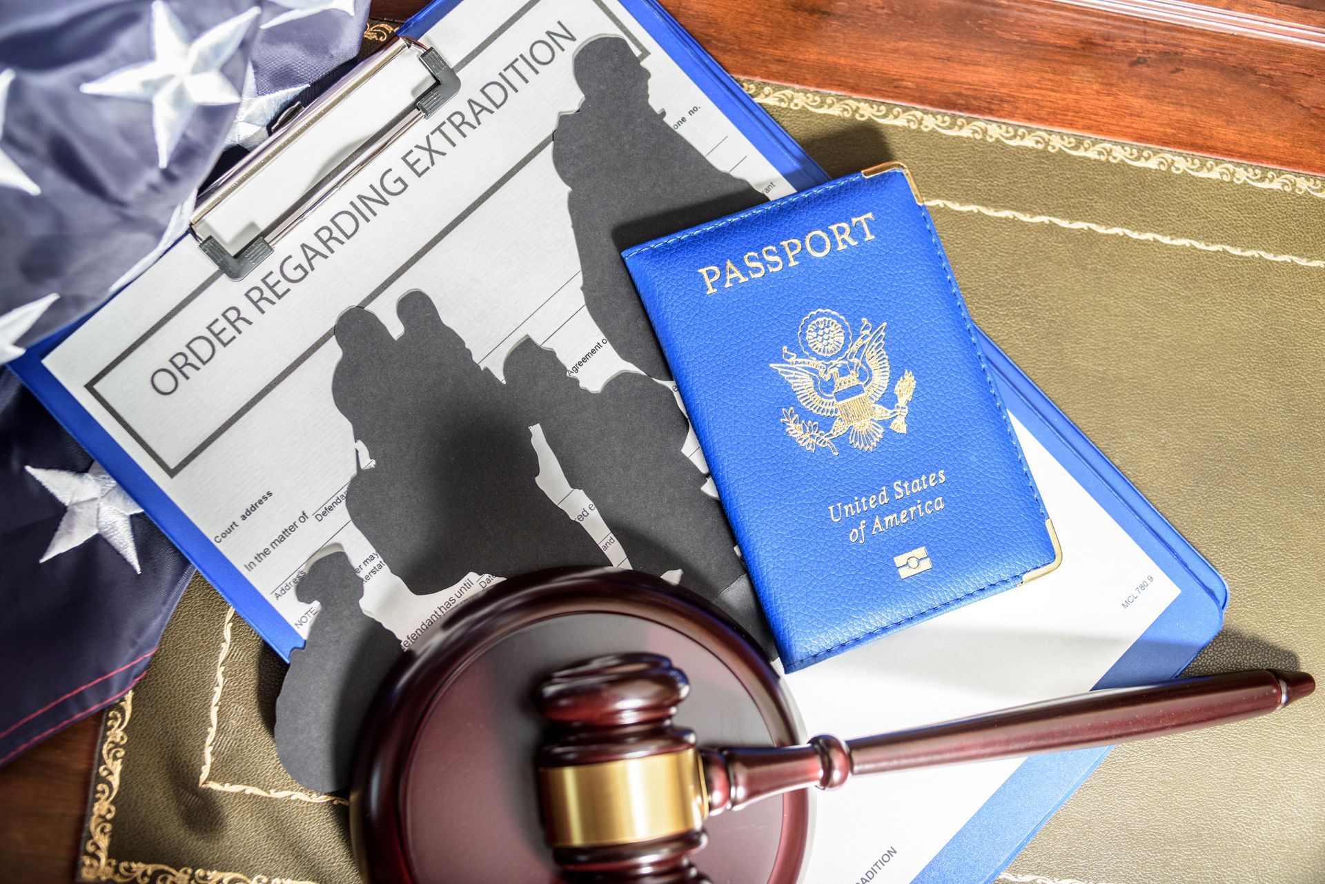 Order regarding extradition document, US passport, gavel, and flag on a desk.
