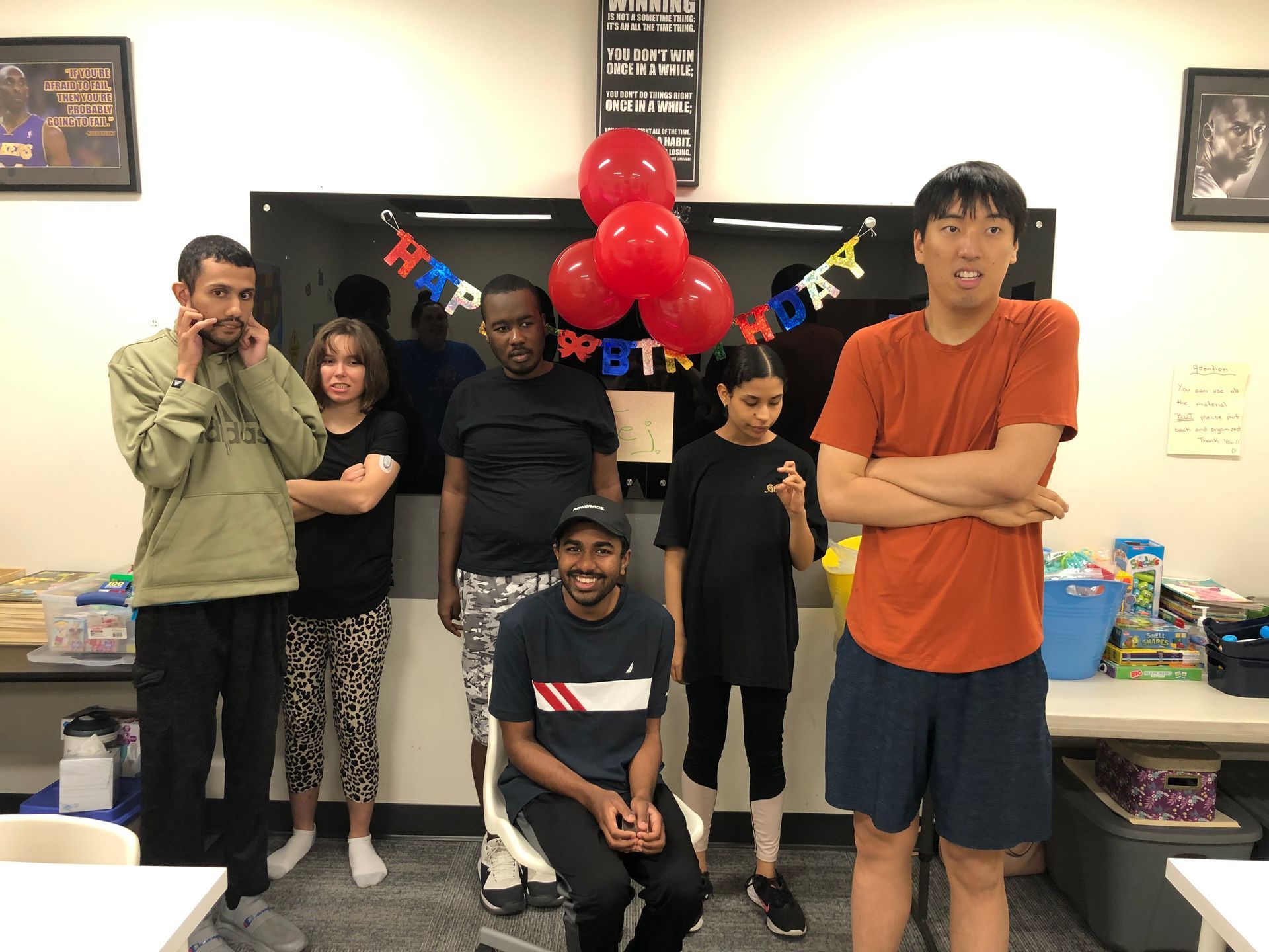 A group of people are posing for a picture in a room with balloons.