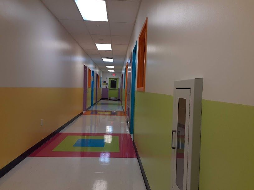 Bright hallway with colorful floor tiles, wall windows, and a fire hose cabinet on the right.