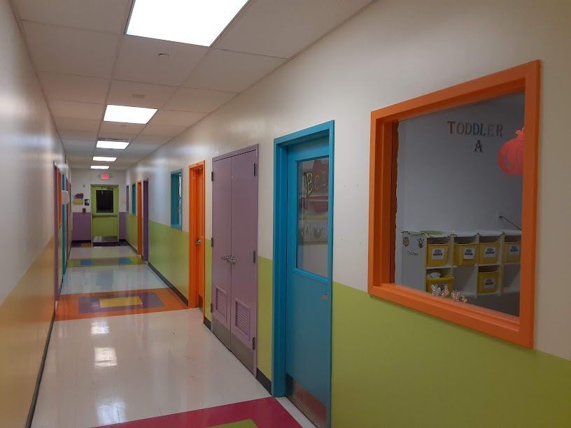 Bright hallway with colorful classroom doors and windows in a school-like building.