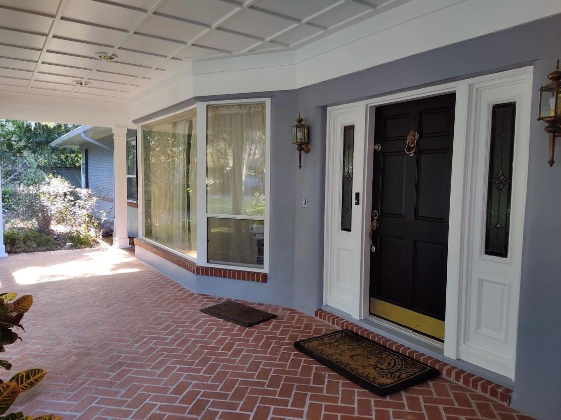 A porch with a black door and white windows